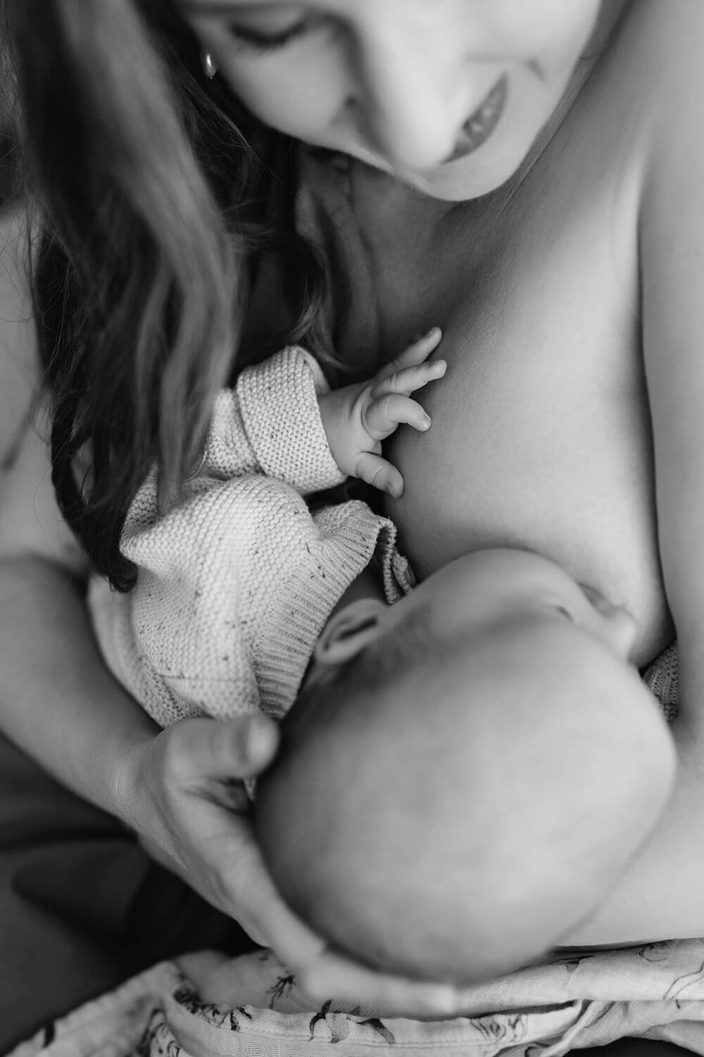 A woman nursing a baby while another child is touching her chest.