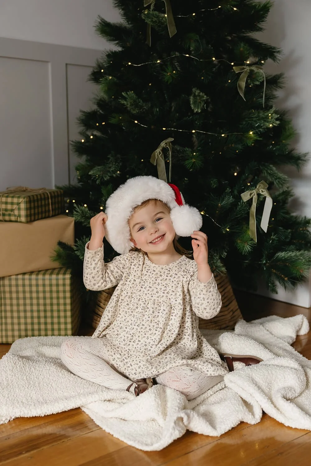 Child wearing a Santa hat during a Christmas mini session at White Cottage South