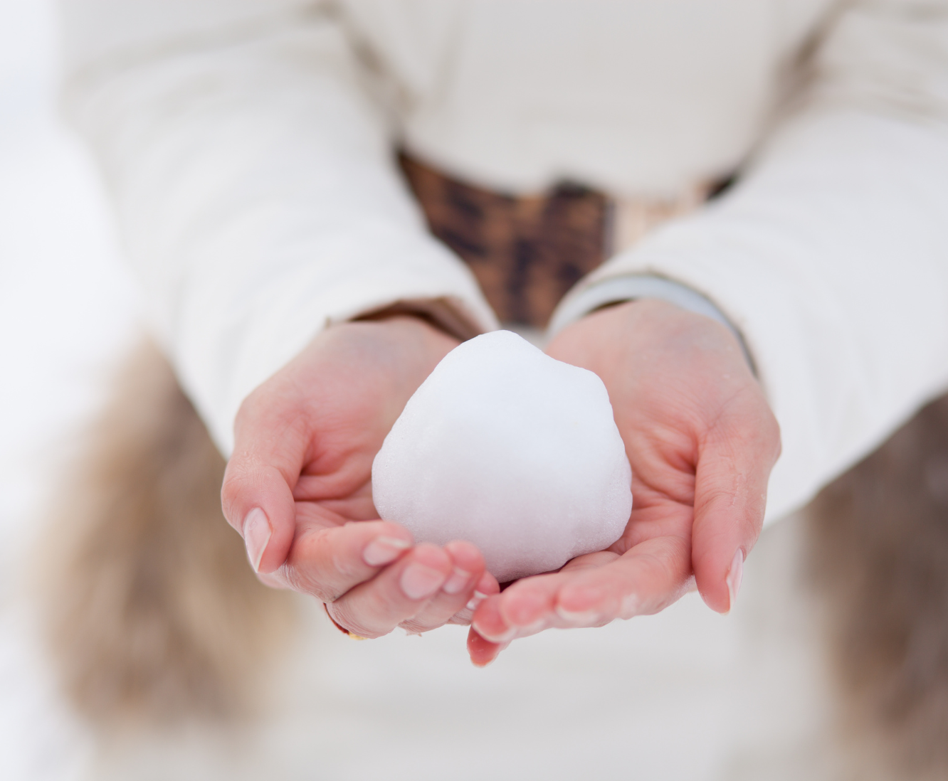 Person holding a heart-shaped snowball with both hands.