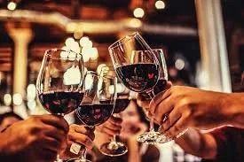 People clinking glasses of red wine in a party or celebration setting.