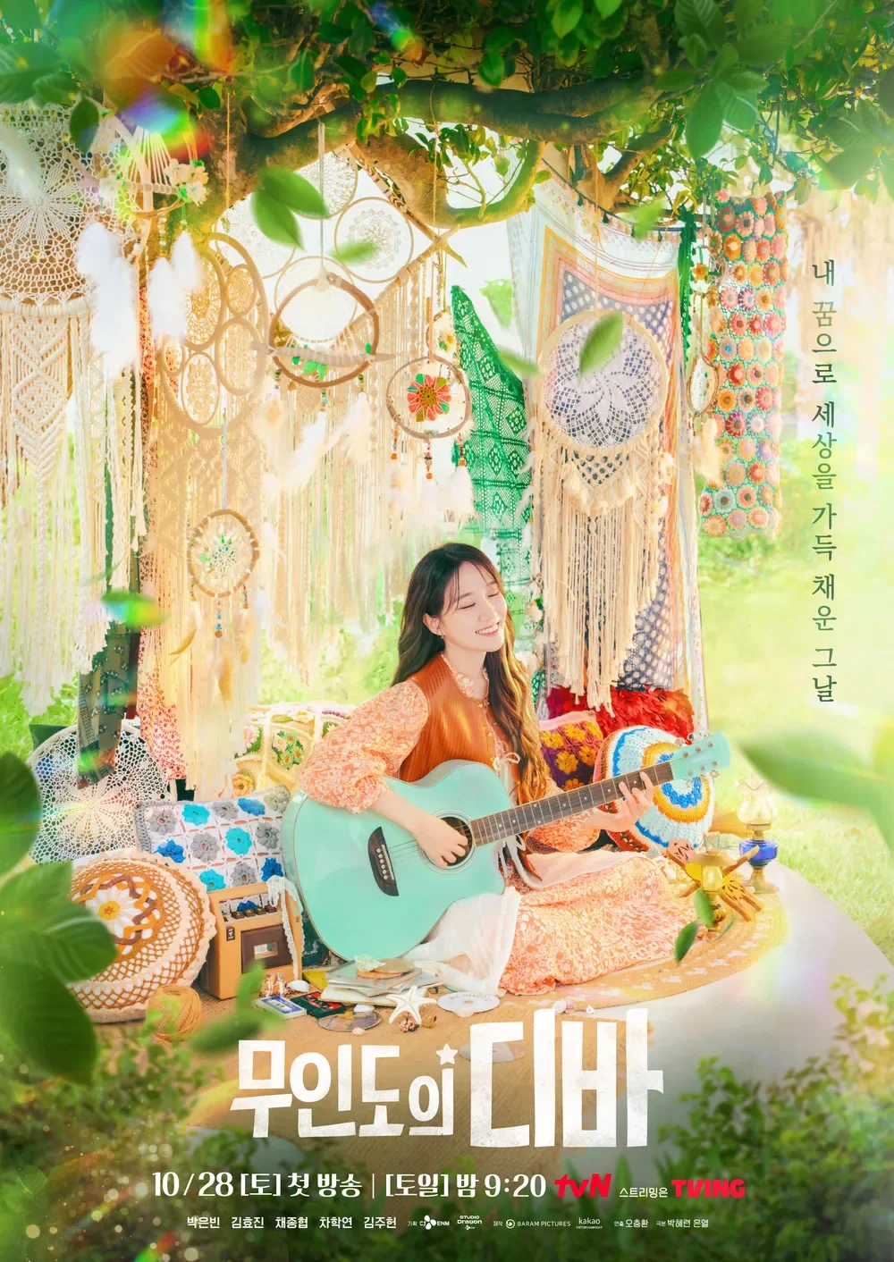 A young woman in orange and cream clothing is sitting on a colorful blanket, playing a turquoise acoustic guitar. She is in a decorated outdoor space with dreamcatchers, crochet hangings, and lush green foliage, illuminated by soft sunlight.