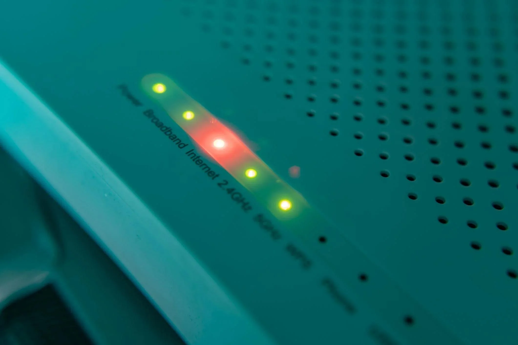 Close-up of a router or modem with multiple LED indicator lights, including green, yellow, and red, showing status. Part of the device's branding and model number is visible.