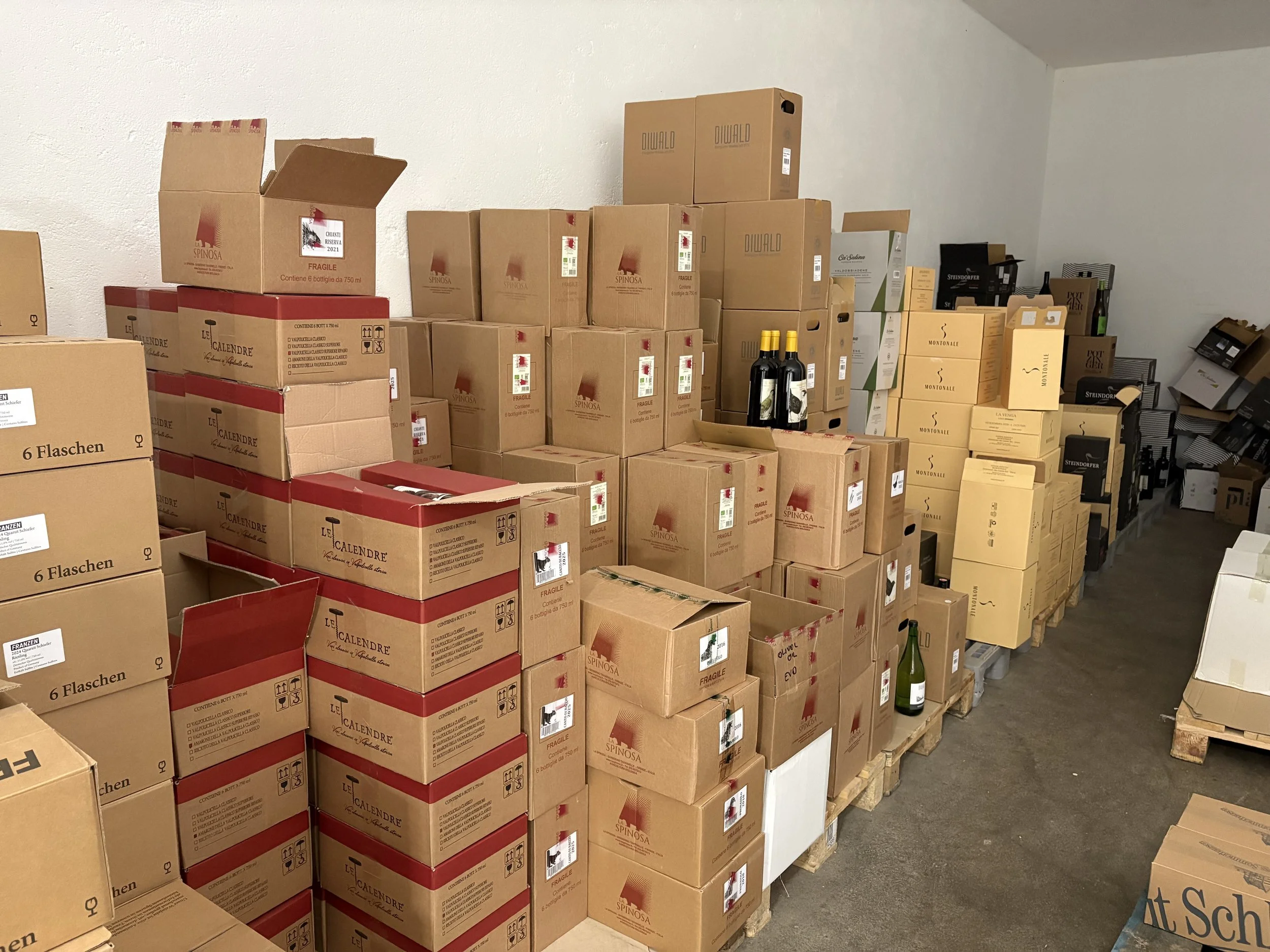 Lagerraum mit vielen Kartons, Weinflaschen und Verpackungen auf Paletten