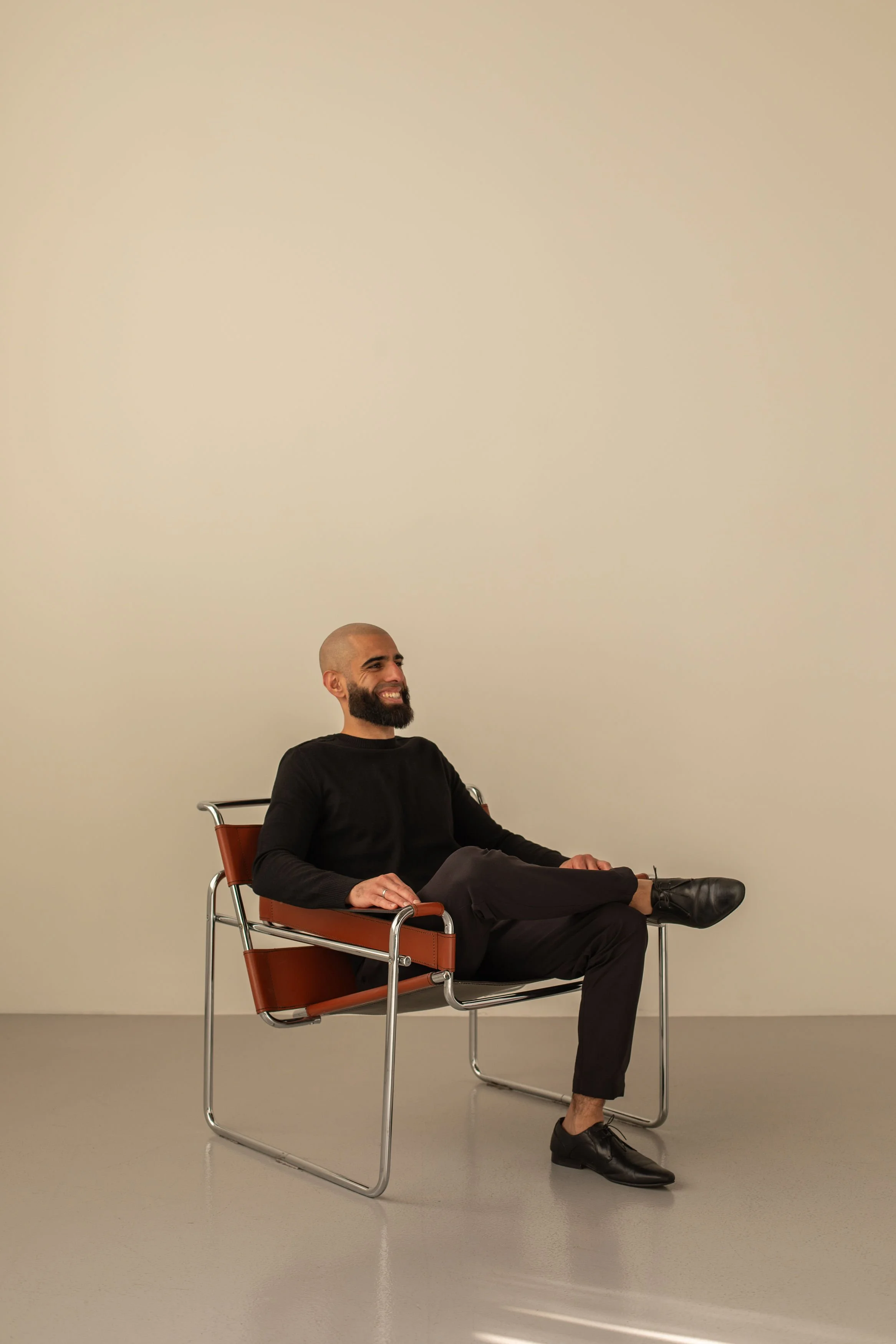 Tariq Abed, Founder and Managing Partner of Siya Studio, seated in a chair against a neutral studio backdrop