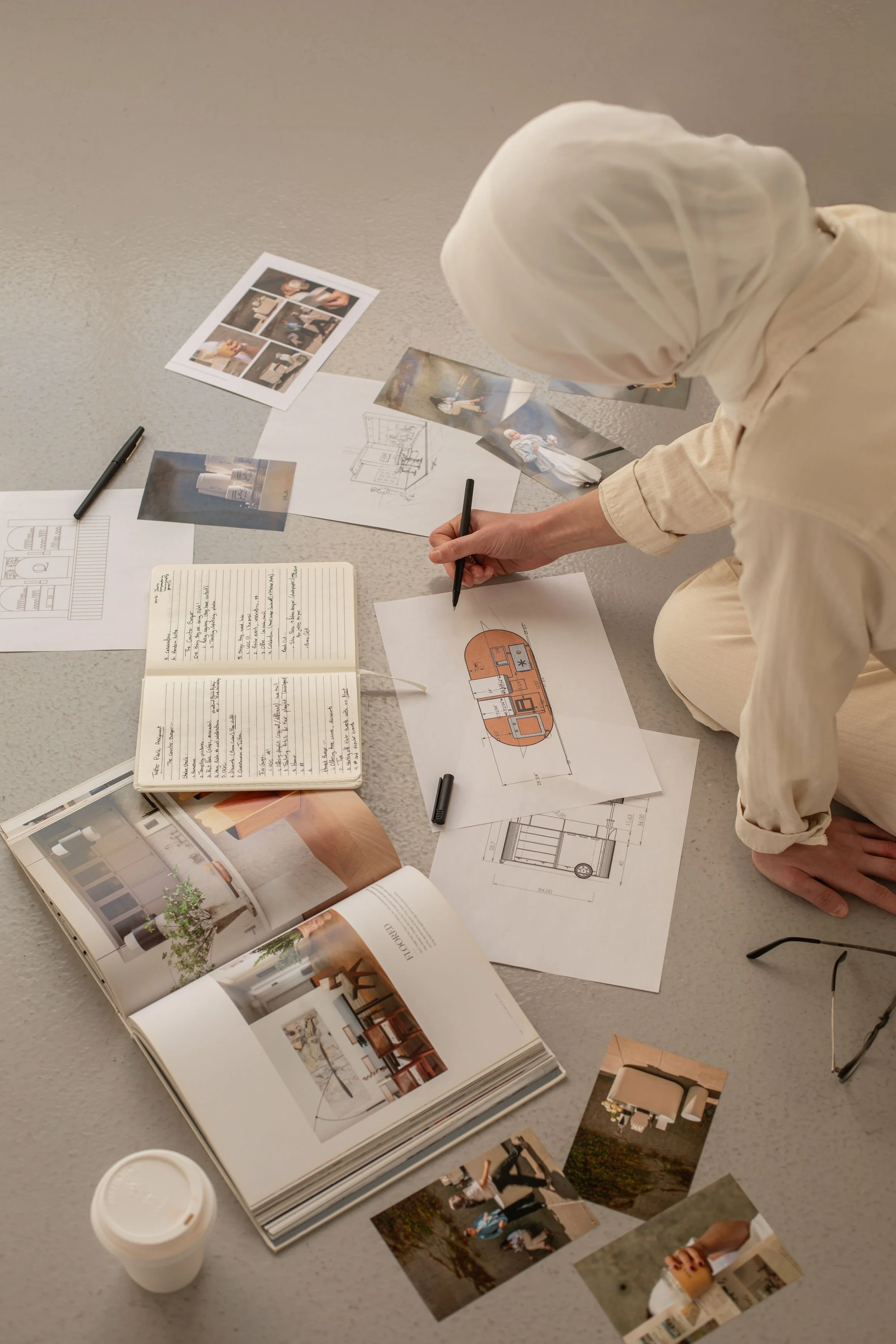 Siya Studio creative director sketching event layout designs surrounded by inspiration photos, architectural drawings, and a design notebook