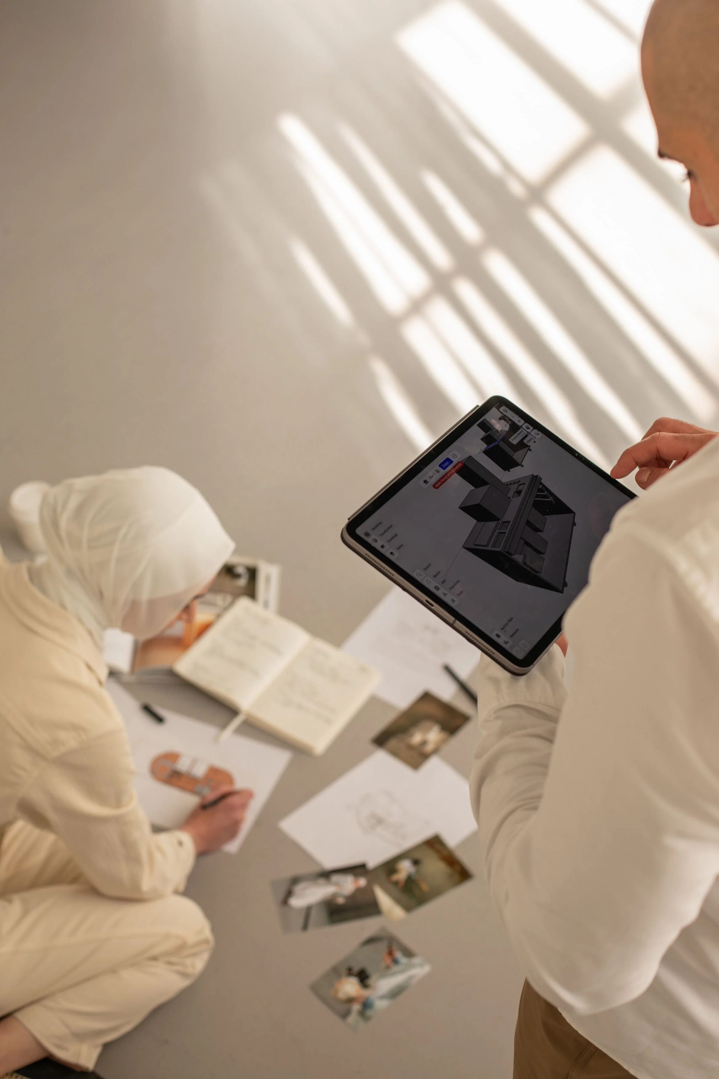 Siya Studio founders reviewing a 3D event build concept on a tablet alongside sketches and inspiration photos during the design process