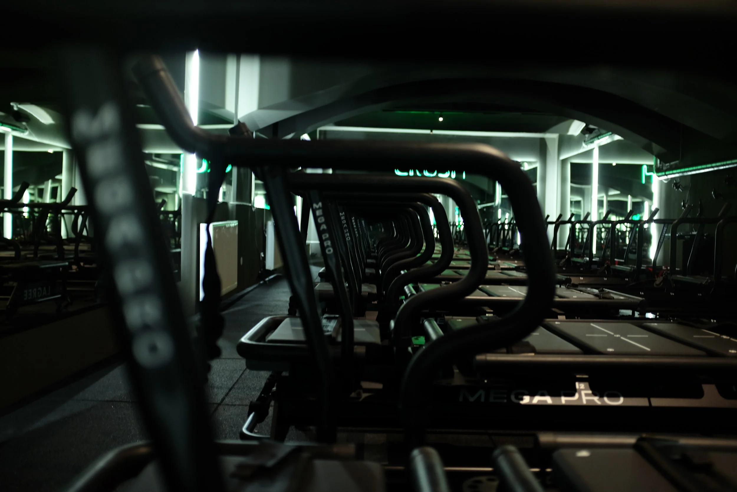 Rows of Lagree Machines with a focus on the machines in a dimly lit gym
