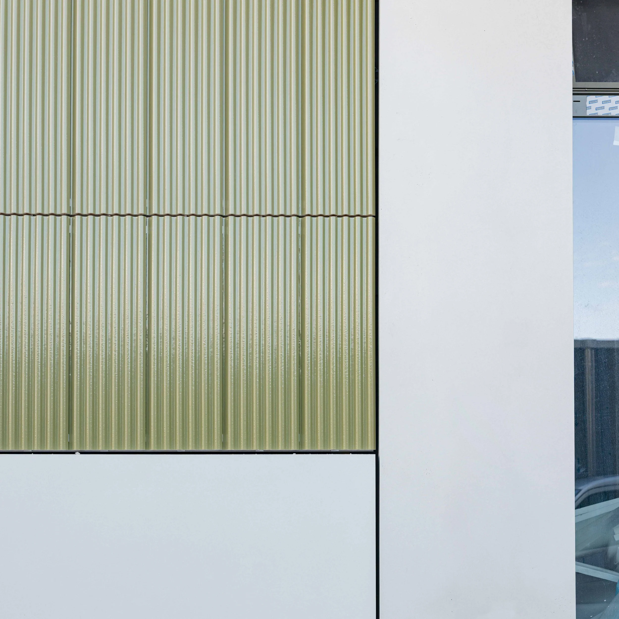 Fassade mit Mineralit und grün-gewellten Keramik-Fassade