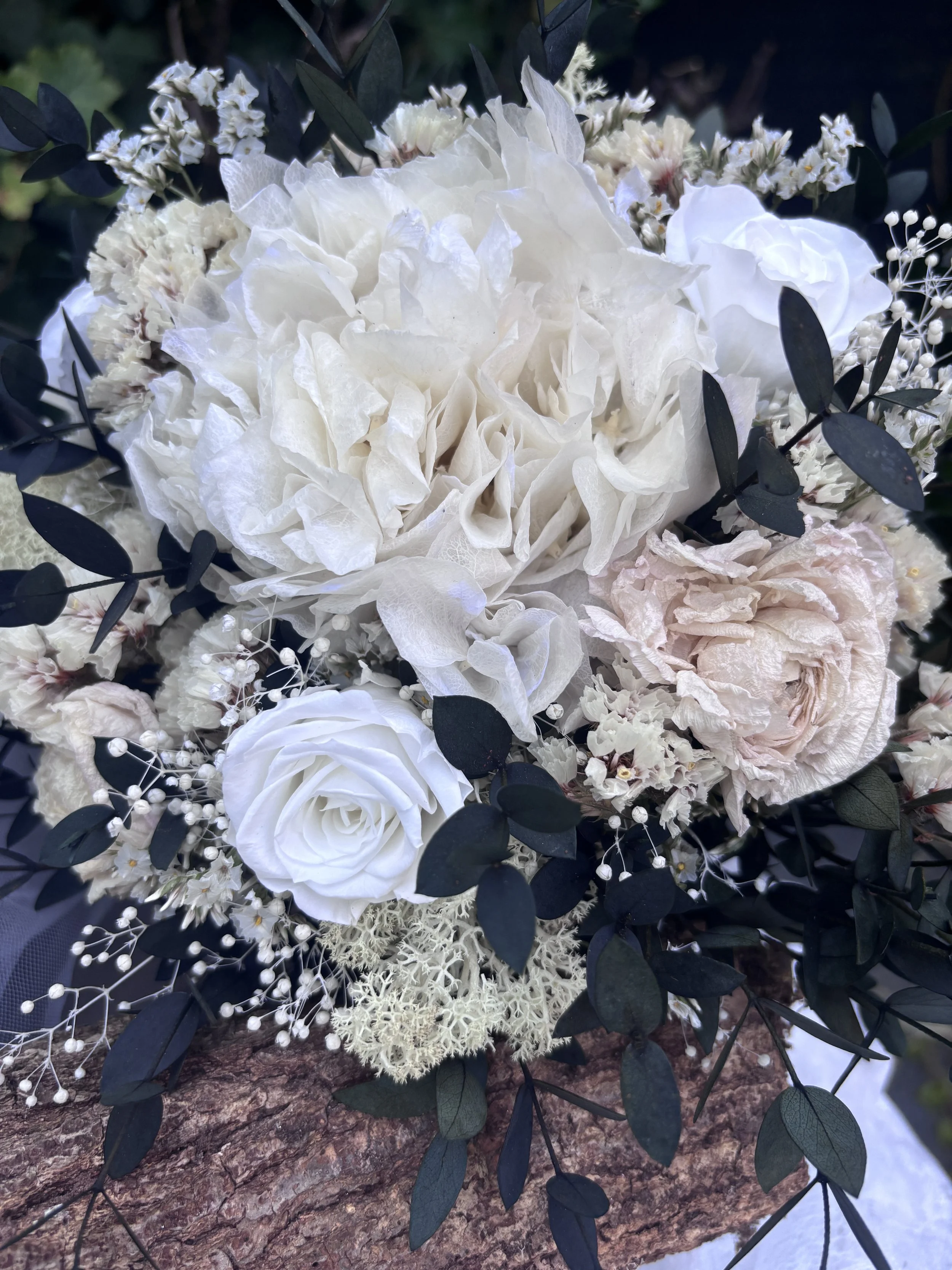 Bouquet de mariée bohème chic en fleurs séchées et stabilisées, composé de pivoines blanches, roses stabilisées, statice blanc, mousse végétale et feuillage d’eucalyptus noir. Cette création artisanale associe élégance, douceur et caractère pour un m
