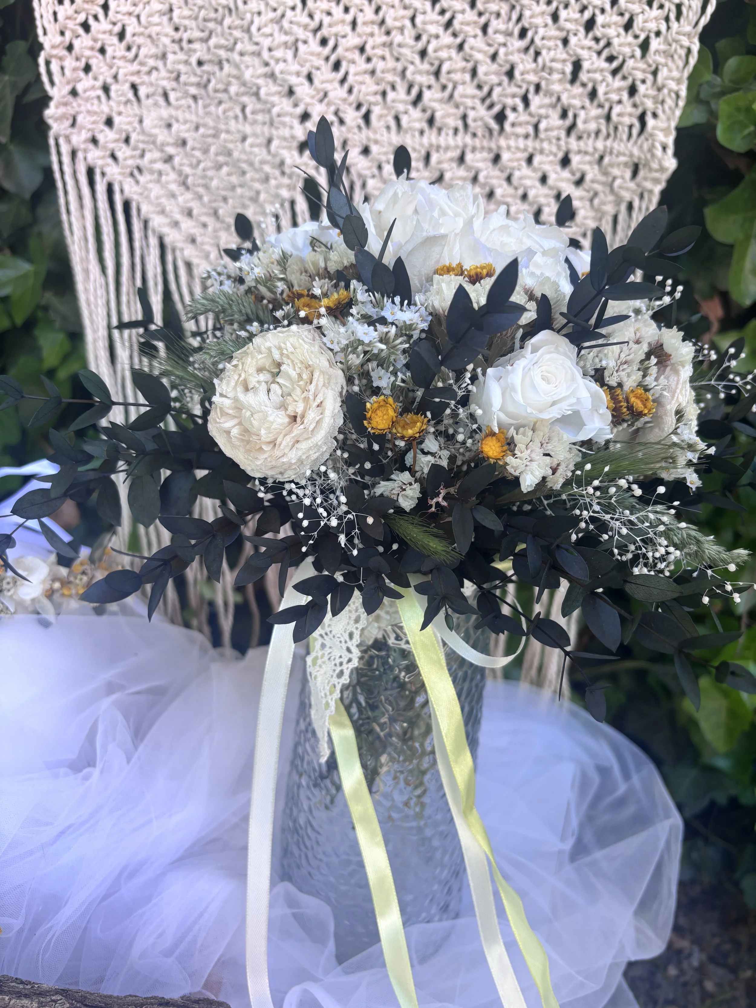 Bouquet de mariée bohème en fleurs séchées et stabilisées, réalisé à la main dans des tons ivoire, blanc cassé, crème et jaune doré. Cette création florale associe hortensia stabilisé, roses éternelles blanches, renoncules séchées, statice, graminées