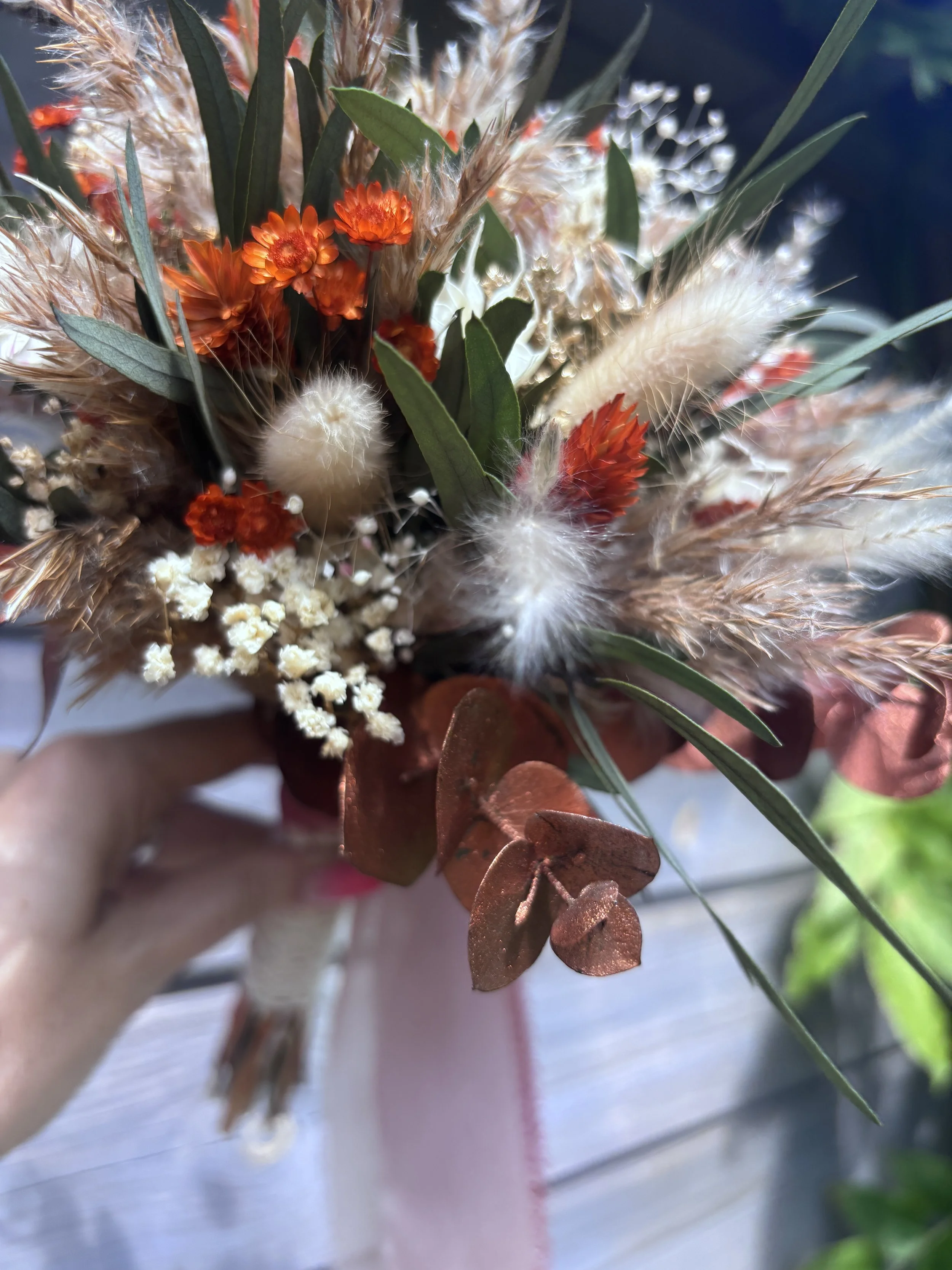Bouquet de mariée en fleurs séchées et stabilisées dans un style bohème champêtre, composé de gypsophile, lagurus, eucalyptus, fleurs terracotta, touches crème et feuillages aux nuances bordeaux. Une création durable et naturelle, idéale pour un mari