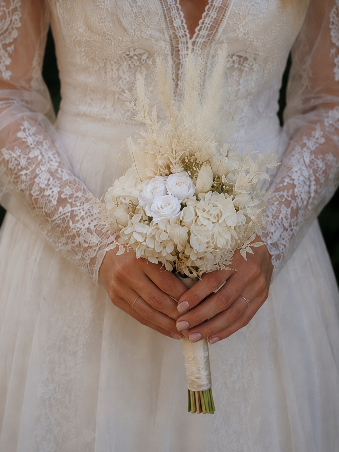 Bouquet de mariée en fleurs séchées et stabilisées blanches, réalisé artisanalement dans un esprit bohème chic et romantique. Cette création florale associe hortensias stabilisés, roses éternelles ornées de perles, arums délicats, feuillages blanchis
