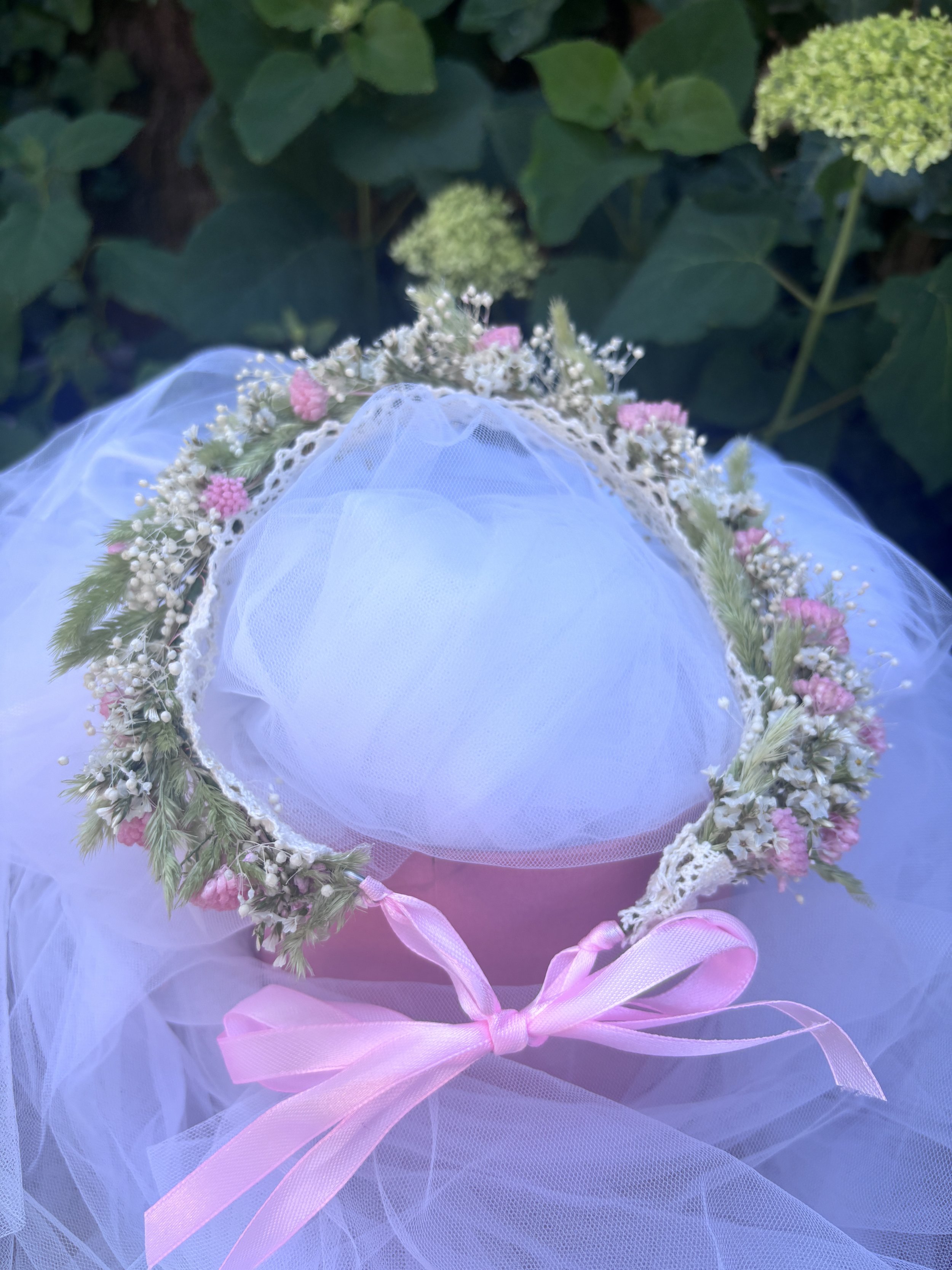 Couronne de fleurs séchées et stabilisées aux teintes rose poudré, blanc naturel et vert tendre. Une création florale bohème et délicate, idéale pour un mariage, une demoiselle d’honneur, une séance photo ou un événement romantique. Réalisée à la mai