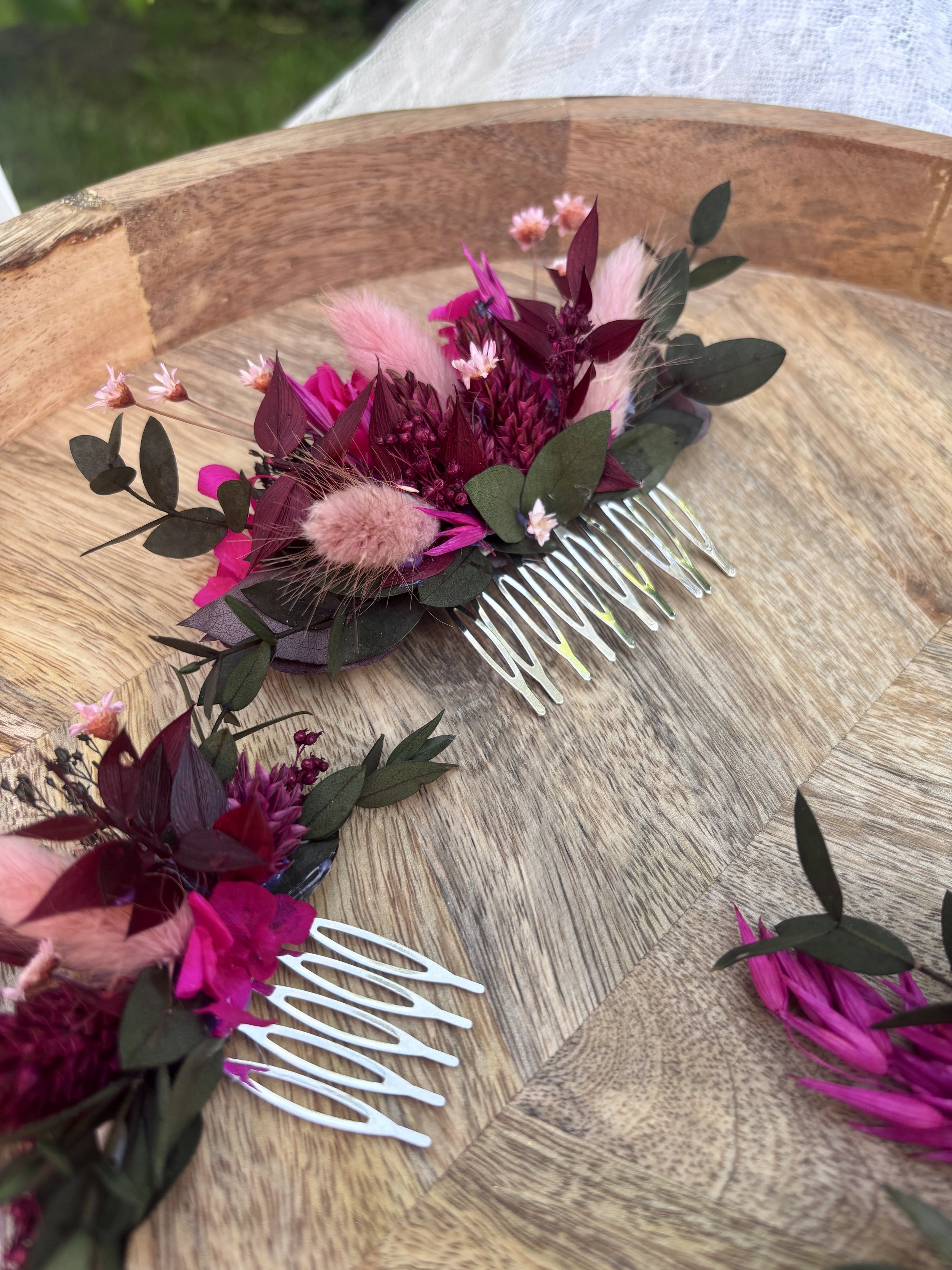 Un peigne décoré de fleurs roses, rouges et vertes sur une table en bois.