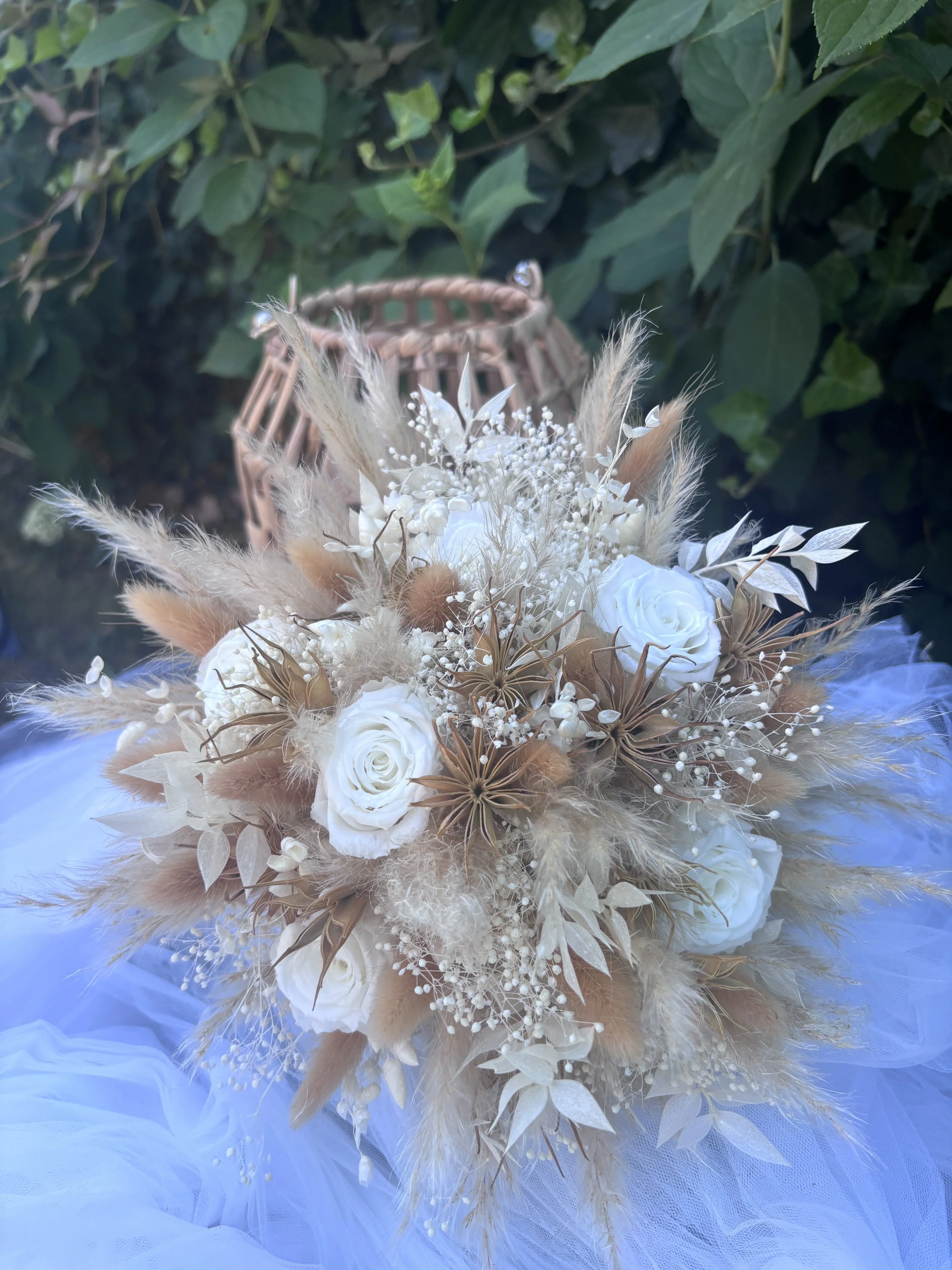 Bouquet de mariée réalisé artisanalement en fleurs séchées et stabilisées. Une création romantique et aérienne mêlant roses blanches, gypsophile, pampas et feuillages naturels dans des nuances ivoire, nude et rose poudré. Création sur mesure par L’At