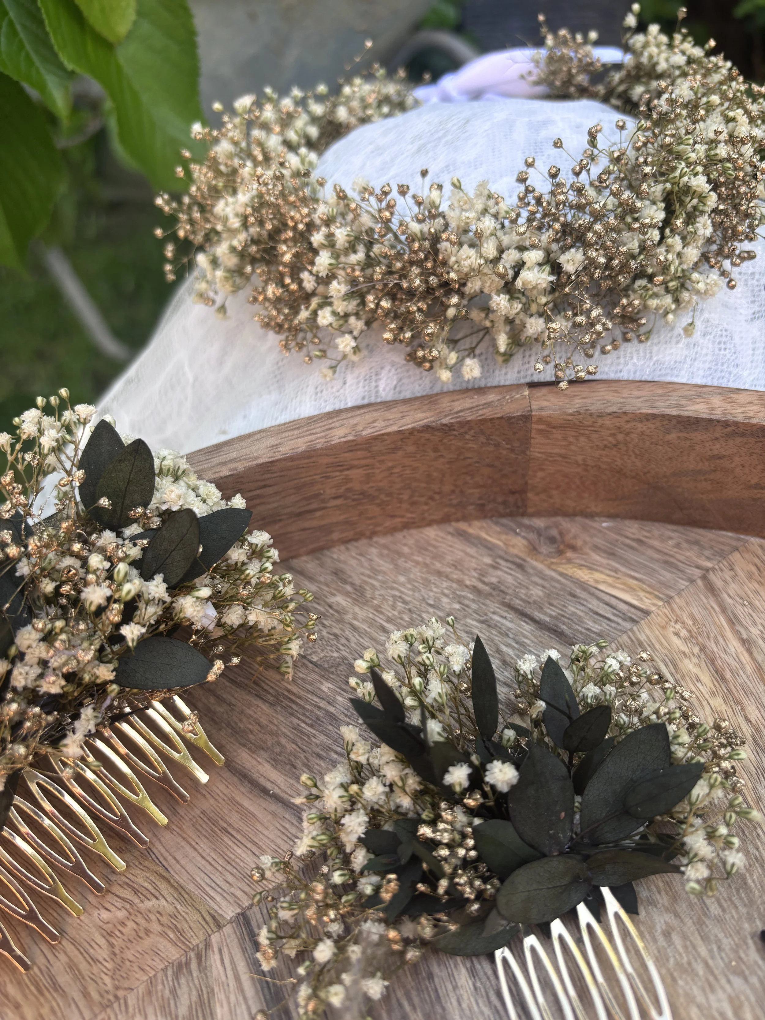 Une couronne de fleurs blanches et de feuilles vertes posée sur une surface en bois.