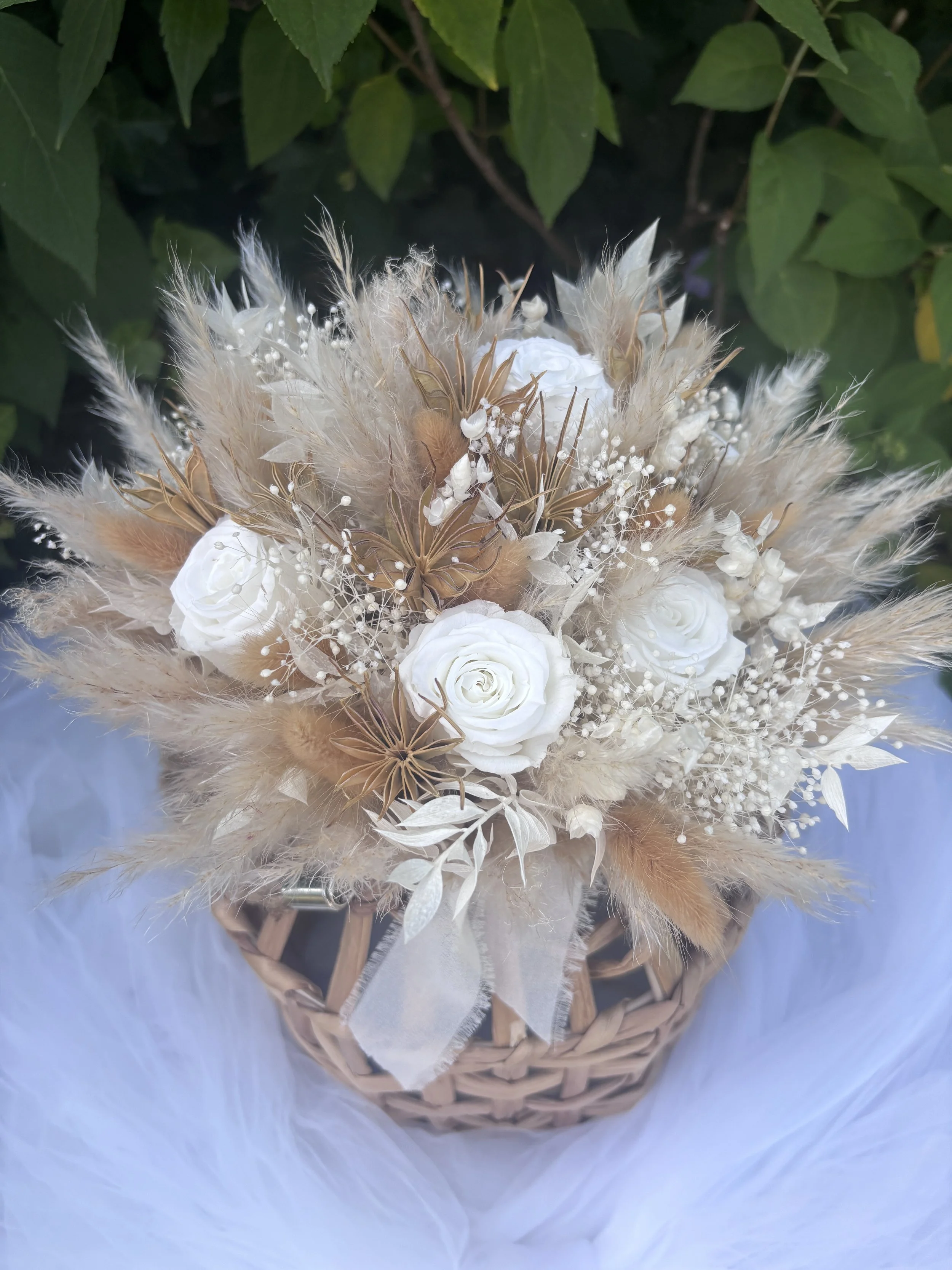 Bouquet de mariée réalisé artisanalement en fleurs séchées et stabilisées. Une création romantique et aérienne mêlant roses blanches, gypsophile, pampas et feuillages naturels dans des nuances ivoire, nude et rose poudré. Création sur mesure par L’At