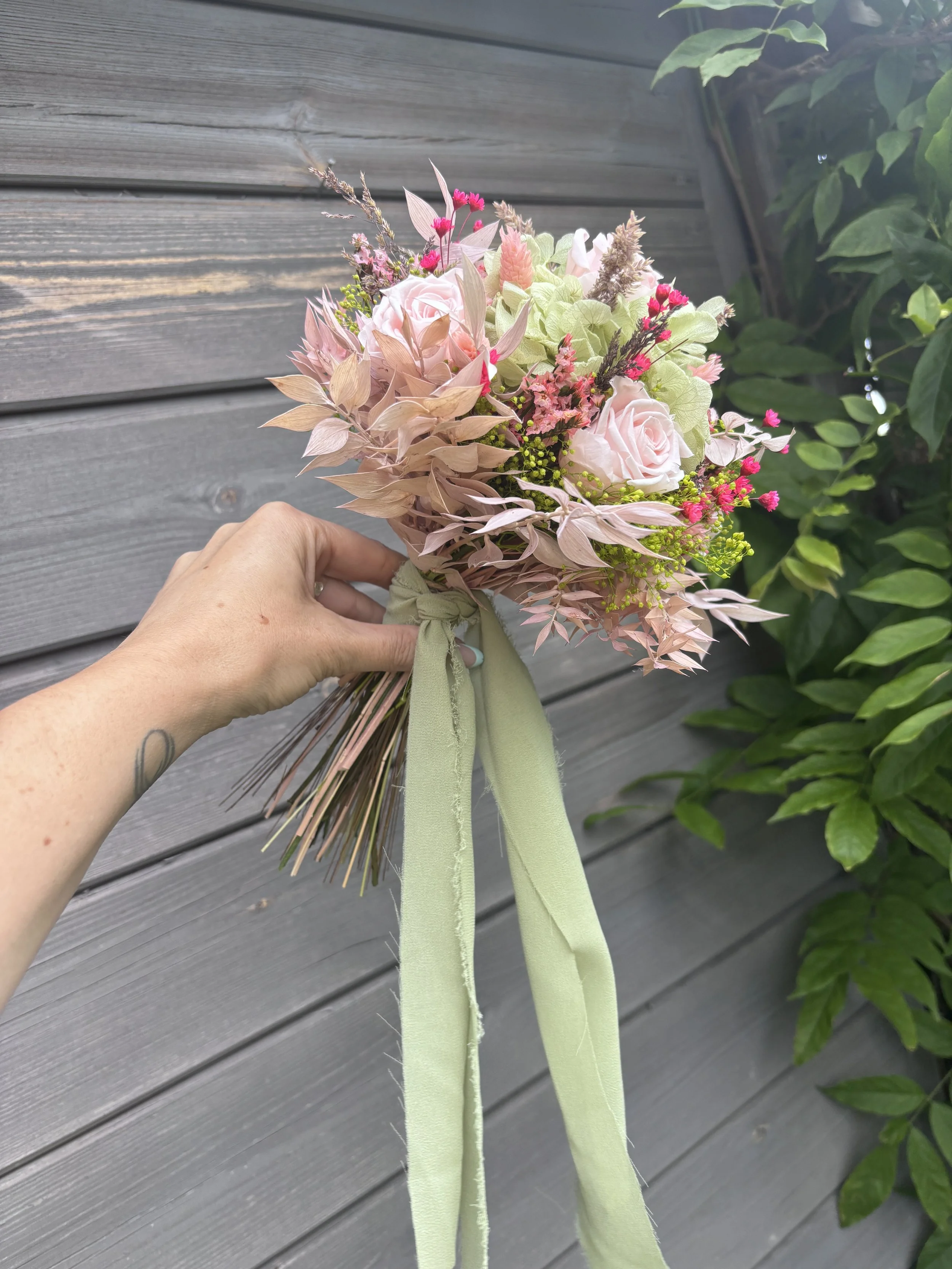 Bouquet de mariée en fleurs séchées et stabilisées aux tons rose poudré, vert sauge et beige naturel, réalisé à la main par L’Atelier Fleurs & Sens près de Valenciennes. Cette création florale bohème et romantique associe hortensia stabilisé, roses s