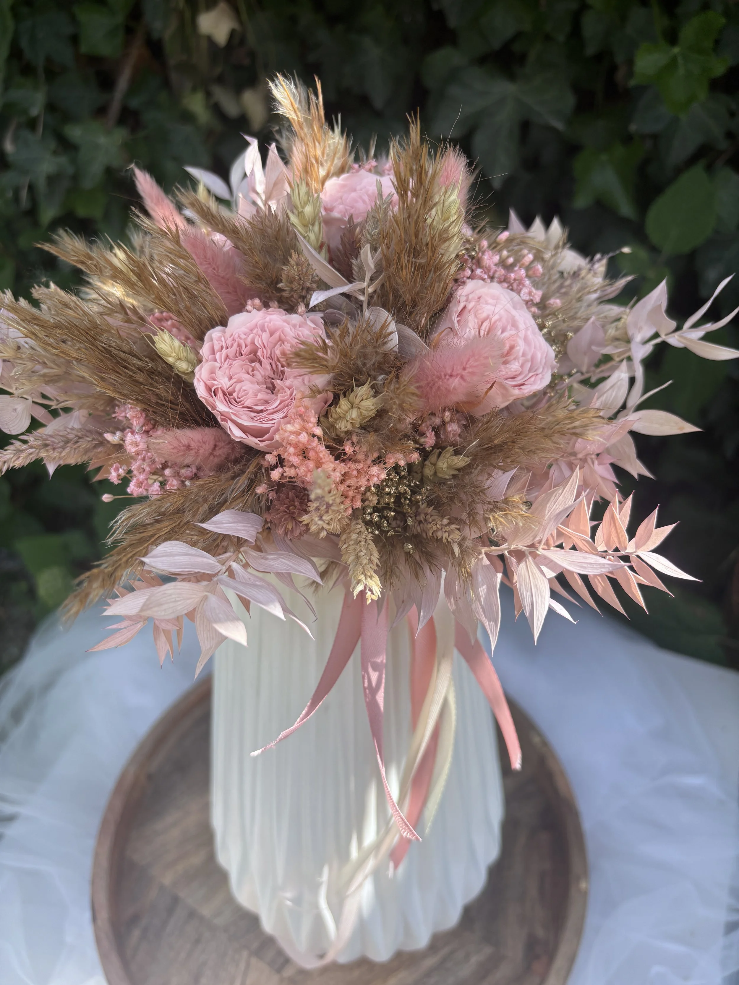 Bouquet de mariée bohème en fleurs séchées et stabilisées dans des tons rose poudré, nude et beige naturel. Création artisanale réalisée par L’Atelier Fleurs & Sens à Saint-Saulve, près de Valenciennes. Composé de roses stabilisées premium, lagurus r