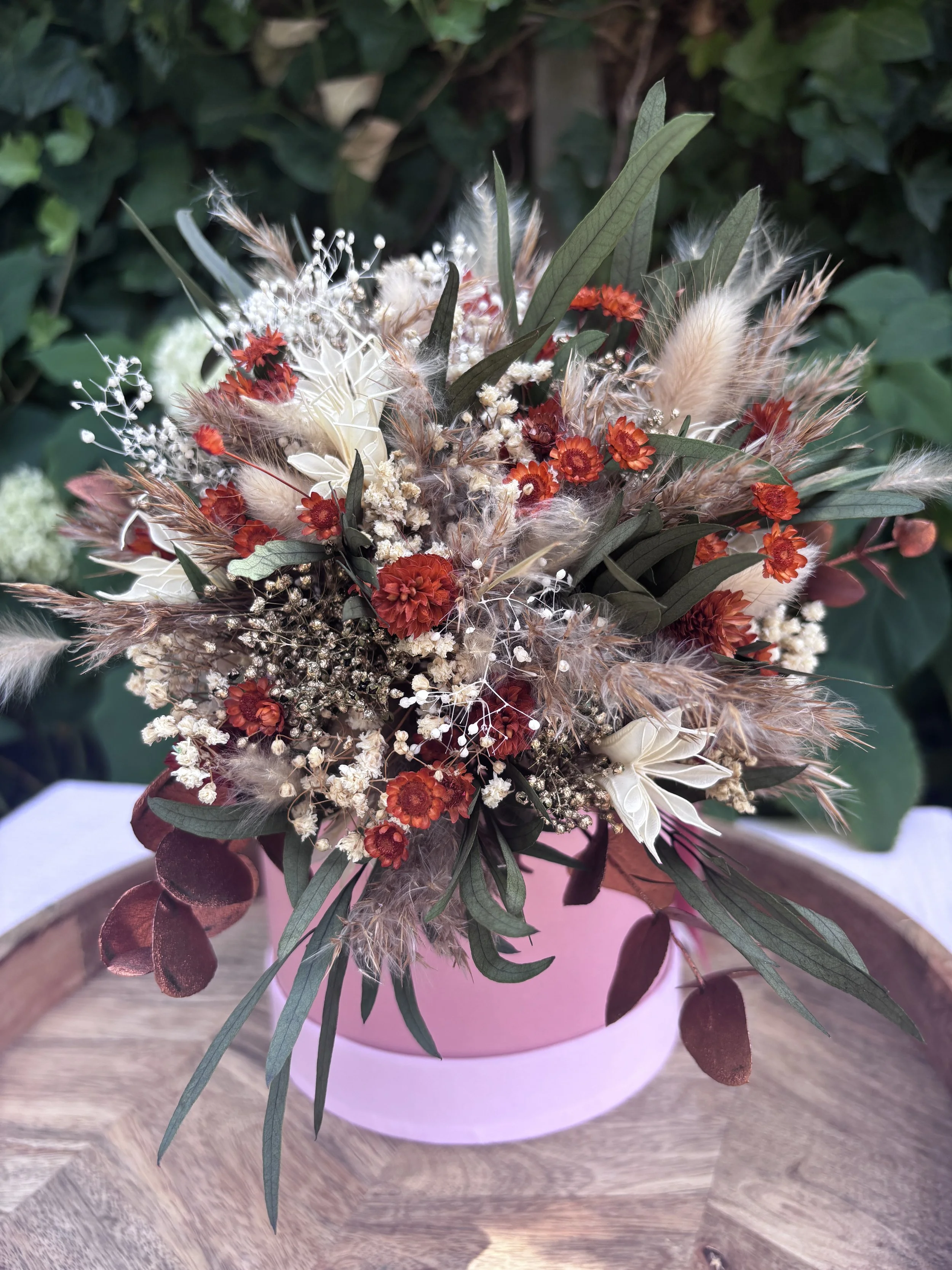 Bouquet de mariée en fleurs séchées et stabilisées dans un style bohème champêtre, composé de gypsophile, lagurus, eucalyptus, fleurs terracotta, touches crème et feuillages aux nuances bordeaux. Une création durable et naturelle, idéale pour un mari