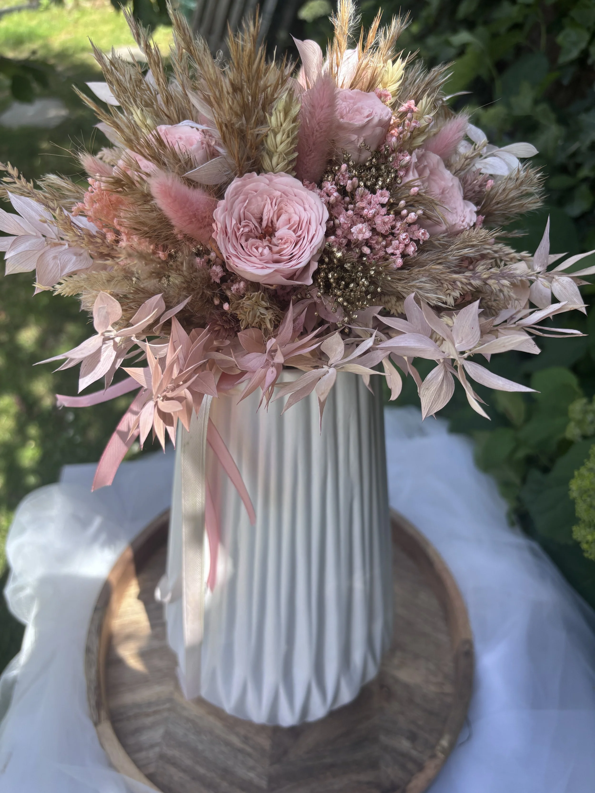 Bouquet de mariée bohème en fleurs séchées et stabilisées dans des tons rose poudré, nude et beige naturel. Création artisanale réalisée par L’Atelier Fleurs & Sens à Saint-Saulve, près de Valenciennes. Composé de roses stabilisées premium, lagurus r