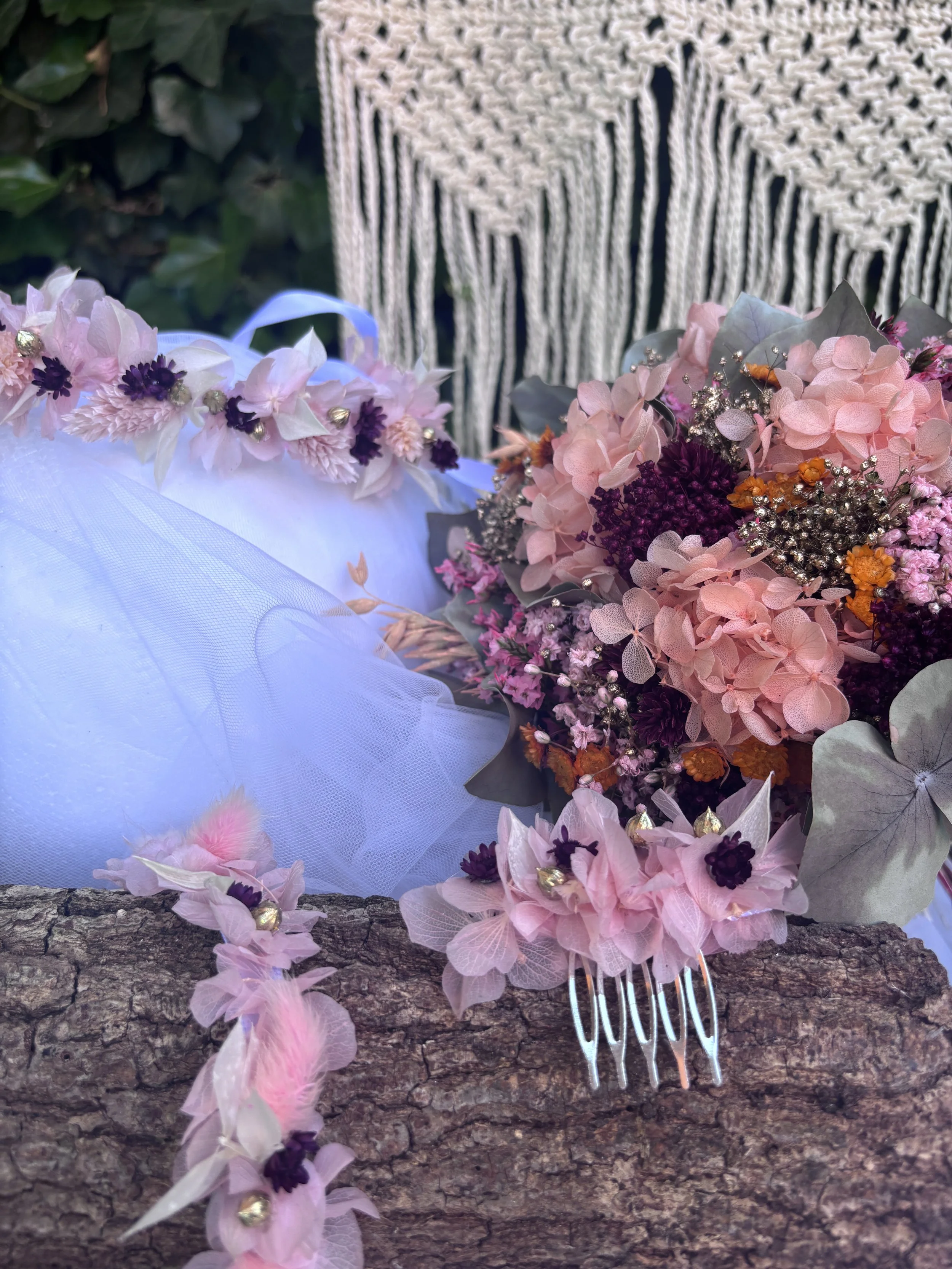 Présentation d'une corbeille de fleurs avec un bouquet de fleurs roses, violettes et orange, accompagnée d'un peigne blanc en plastique, sur une surface en bois rustique.