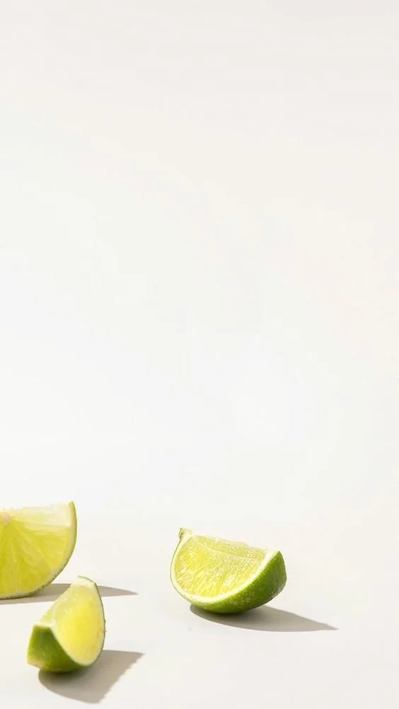 Lemon and lime wedges on a white surface with a plain background.