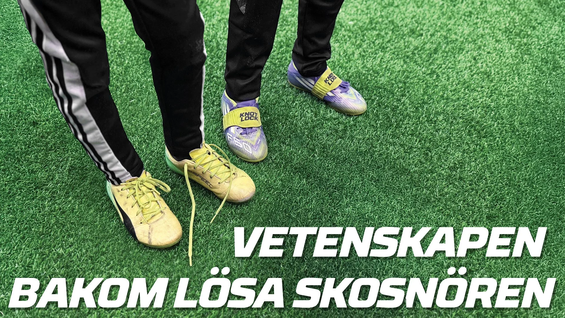 Close-up of two people standing on green artificial turf, wearing sports shoes and athletic pants. One person is wearing yellow soccer cleats, and the other is wearing purple and black cleats with a yellow strap.