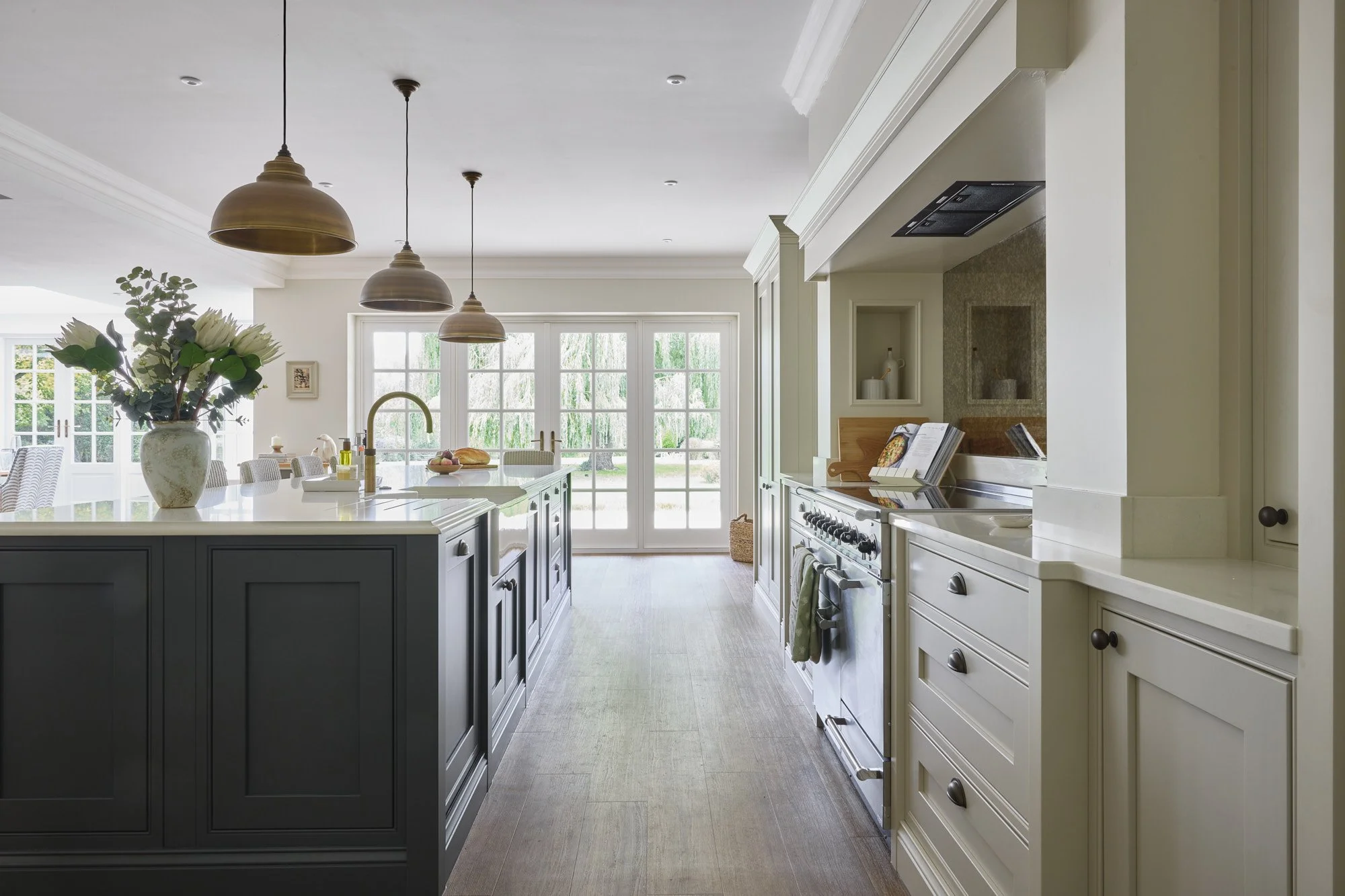 Bright, spacious kitchen with a large island, hanging pendant lights, and a view of the backyard through glass doors.