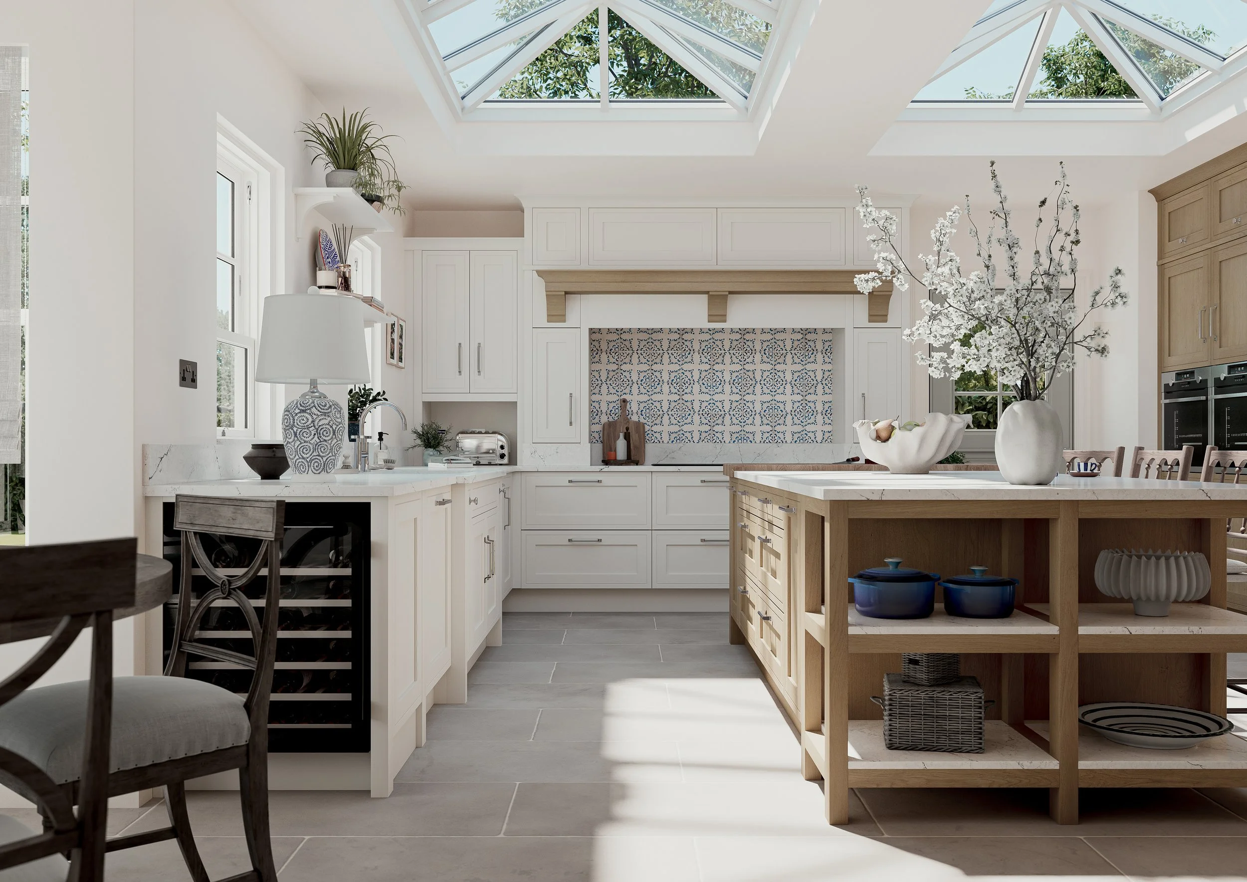 Bright kitchen with a skylight ceiling, white cabinets, a wooden kitchen island with decor, and a large white vase with white blossoms.