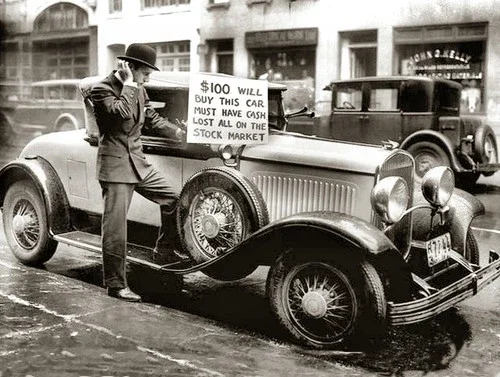 A man in early 20th-century attire standing next to a vintage car with a sign that reads, "$100 will buy this car. Must have cash lost all on the stock market."