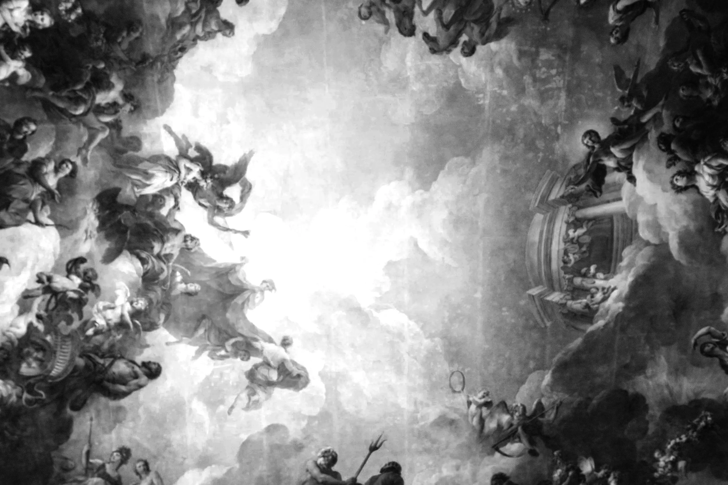 A classical ceiling fresco painting featuring angels and cherubs among clouds, with intricate architectural details around the edges.