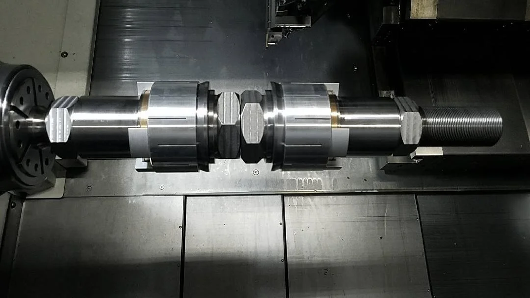 Close-up of a metal machine component with a threaded shaft, mounted on a metal work surface.