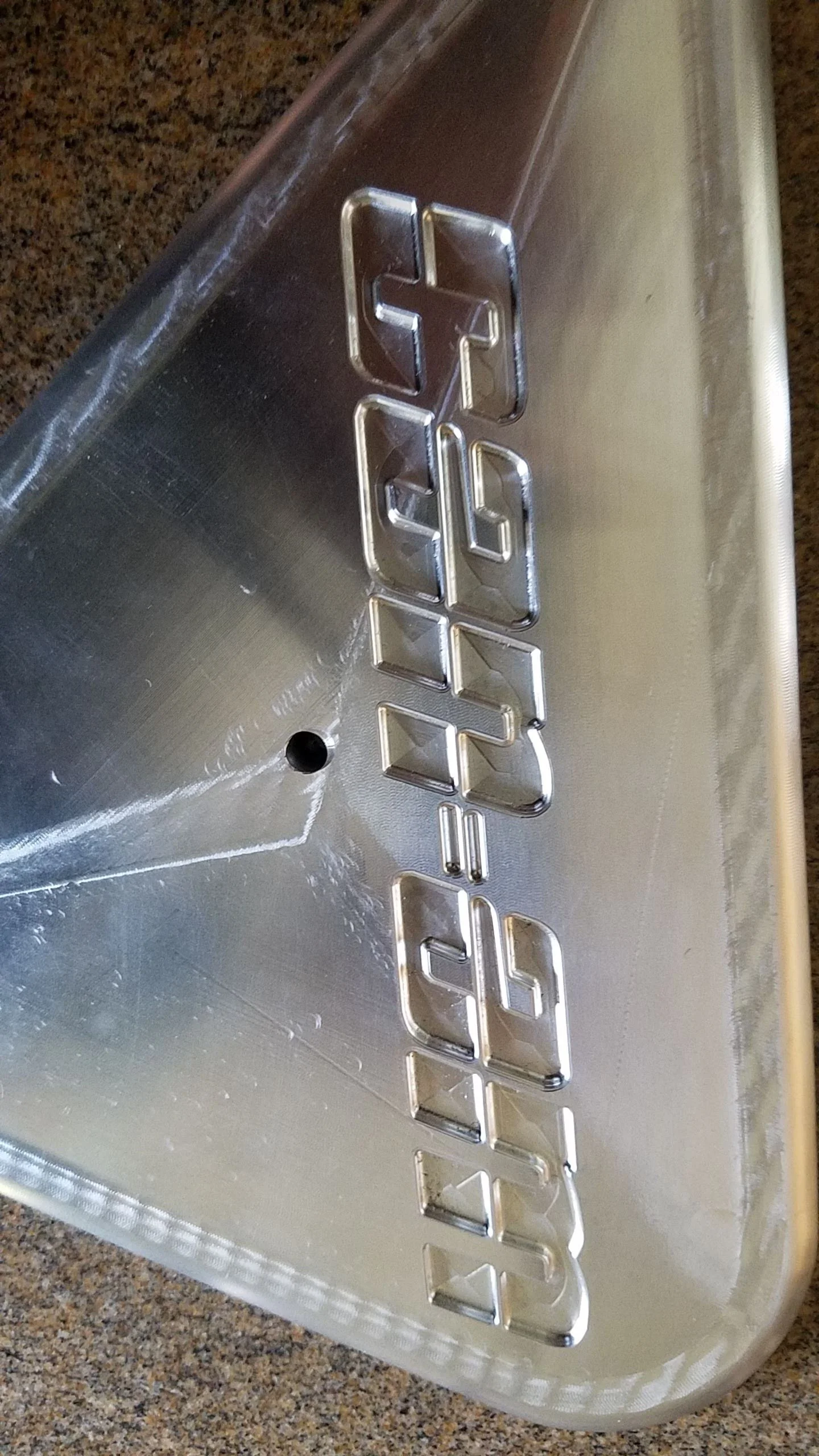 Close-up of a metallic object with the word 'GELAN' engraved on it in block letters.
