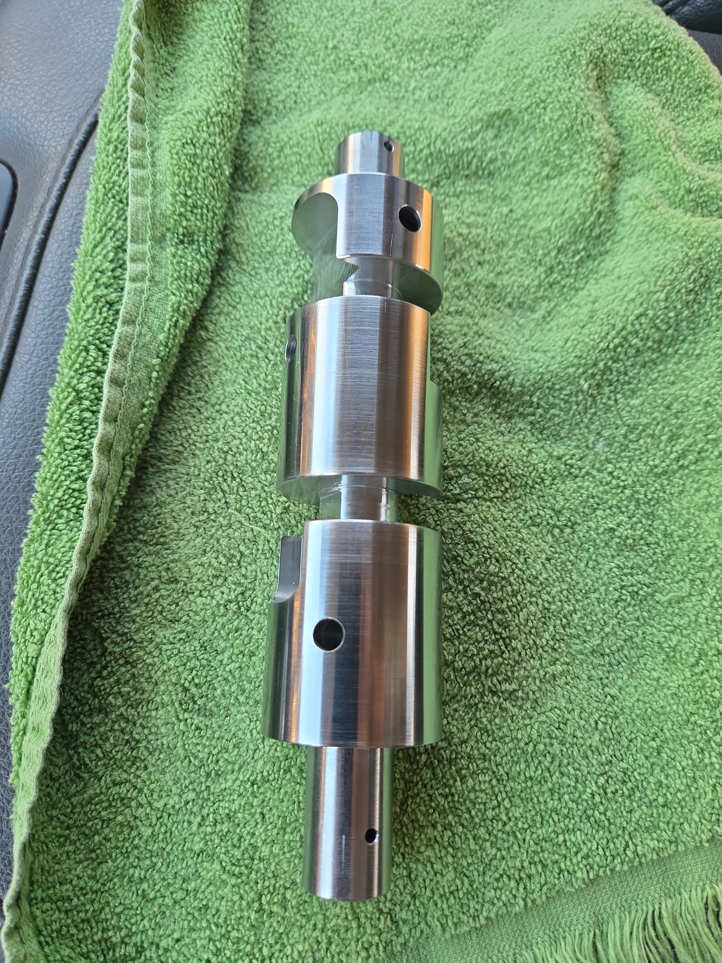 Metal camshaft resting on a green towel.