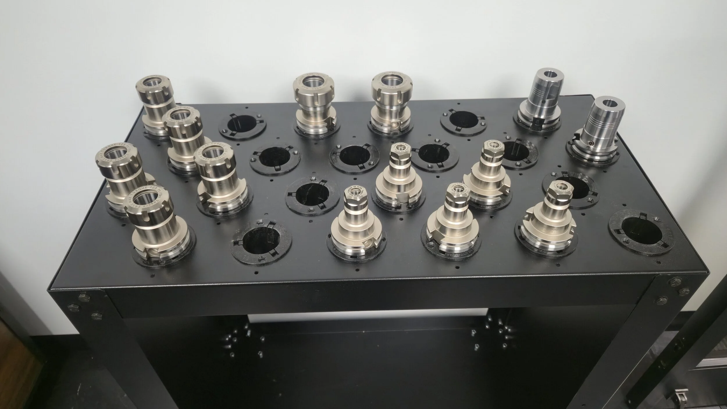 A black table with metal mechanical components, possibly part of a machine or tool, arranged on top.