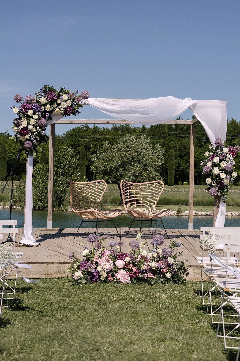 scène de cérémonie laïque au bord d'un lac avec une arche de fleur dan un domaine de la Drôme provençale.