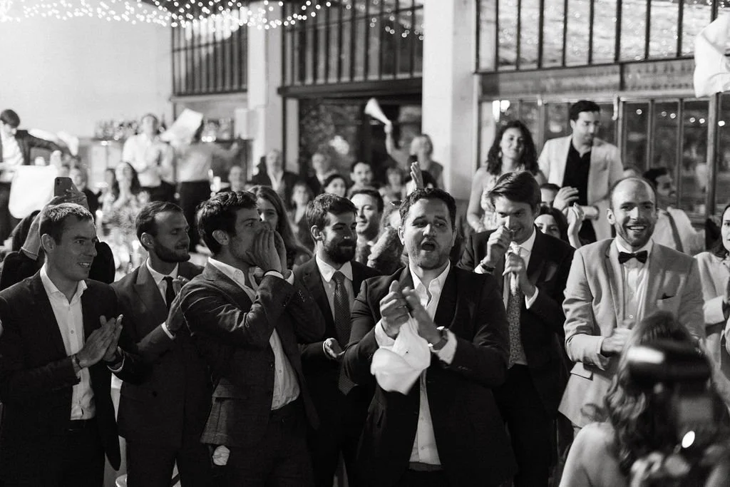 Groupe de personnes habillées élégamment lors d'une célébration de mariage en provence, certaines applaudissant et souriant.