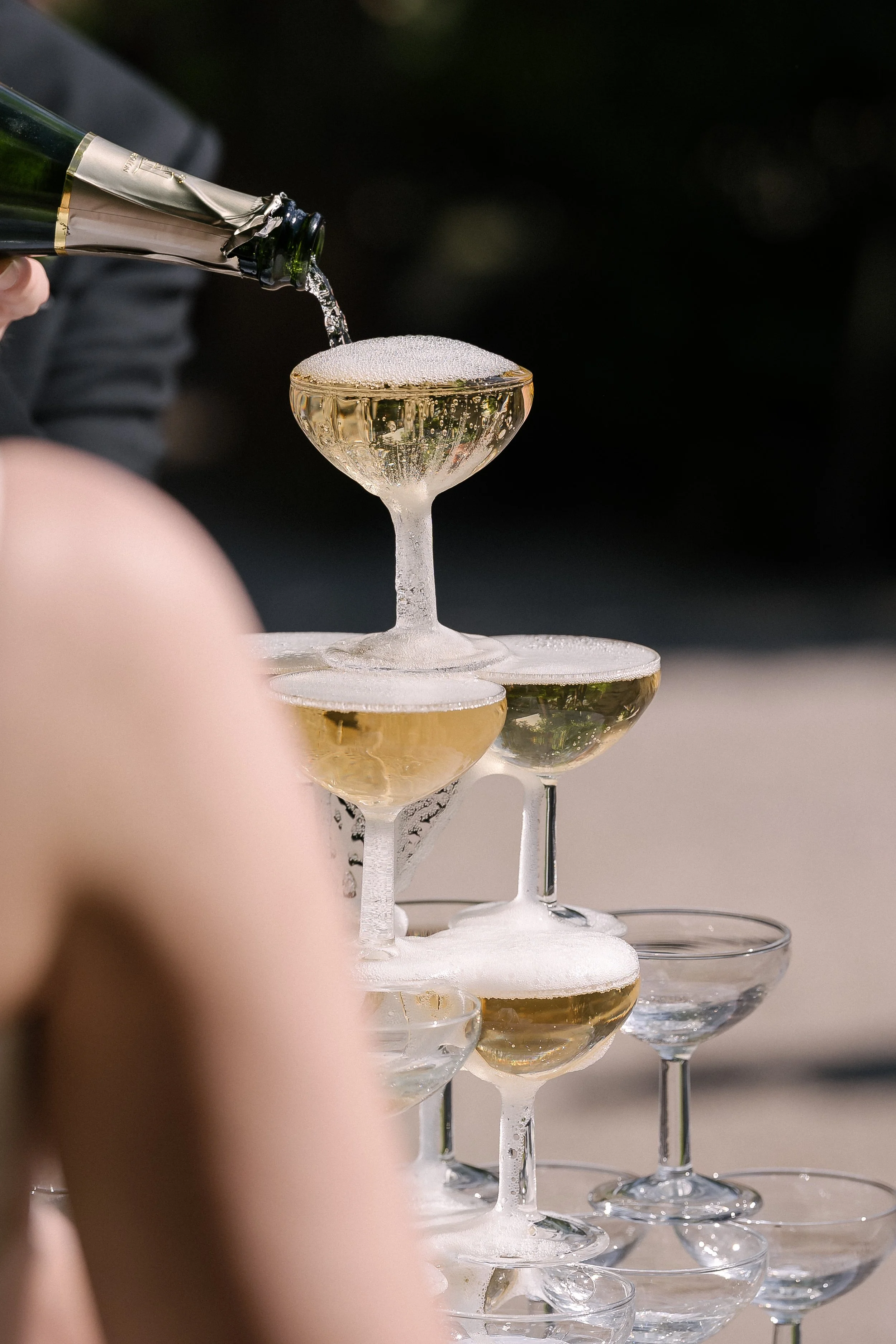 Champagne versé dans une tour de verres à champagne, avec plusieurs étages, dans un domaine en Provence a l'occasion d'un mariage.