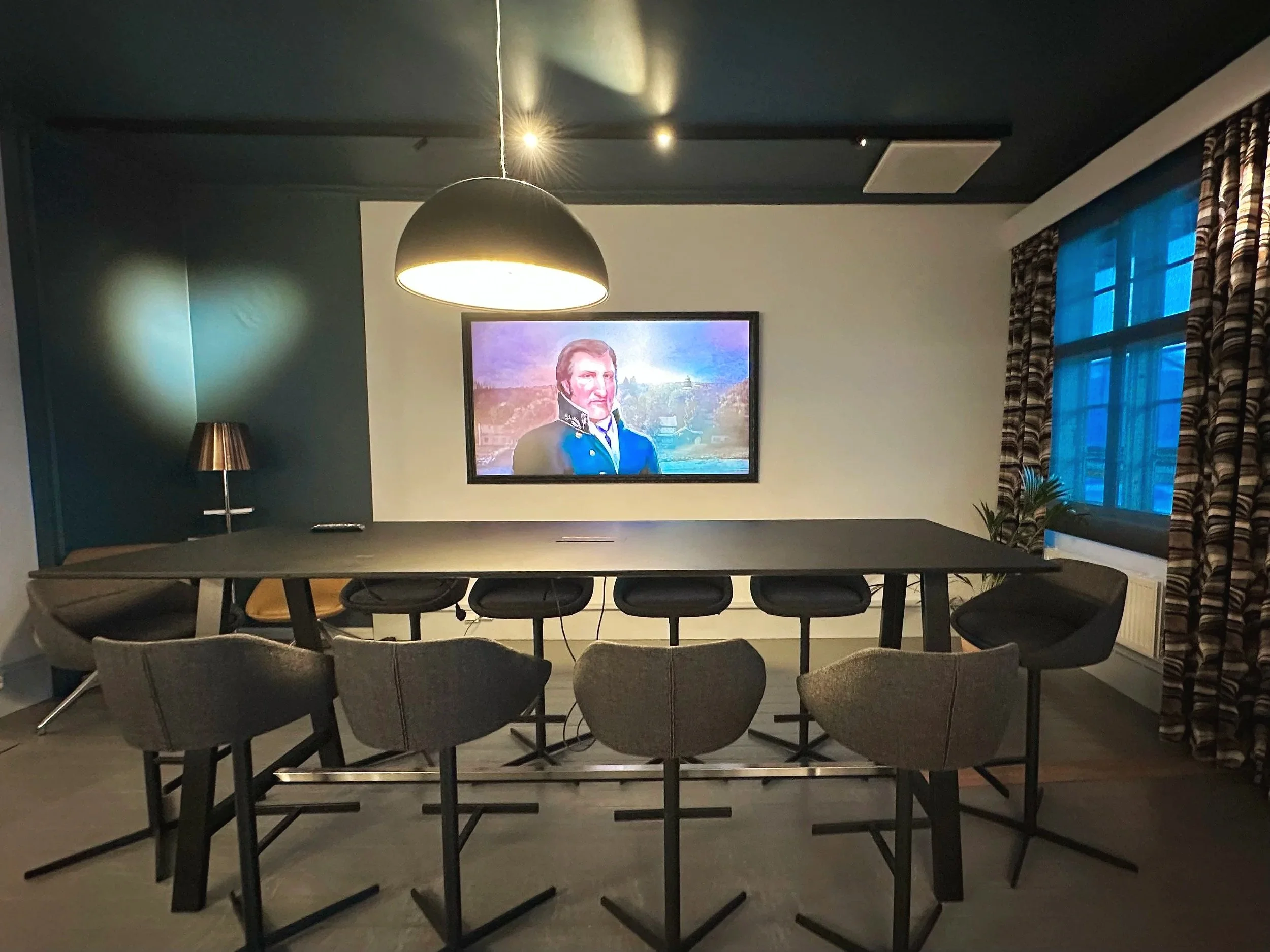 Et mindre møterom med bord, stoler og en TV.