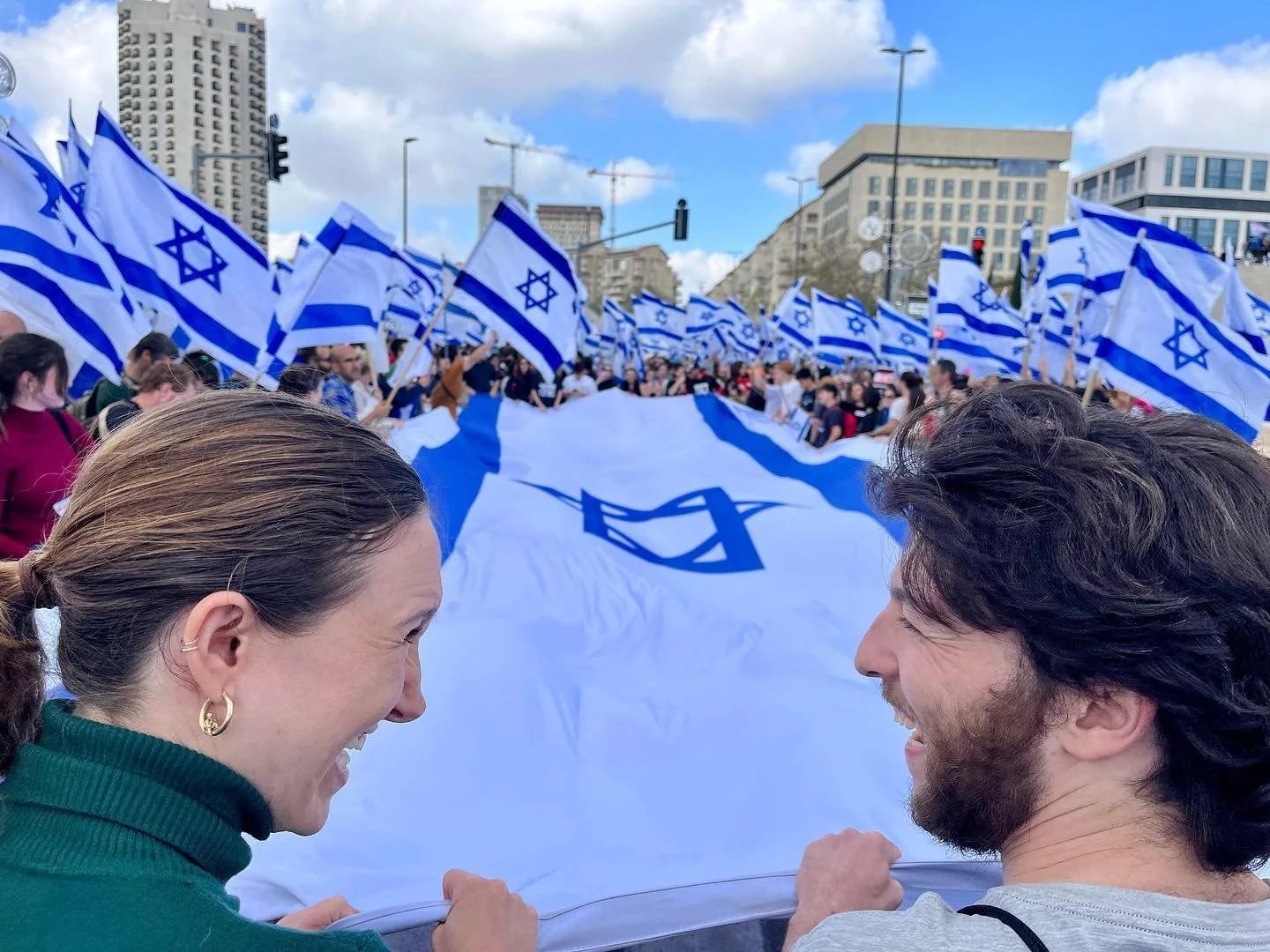 People holding Israeli flags during a demonstration or celebration in an urban area.