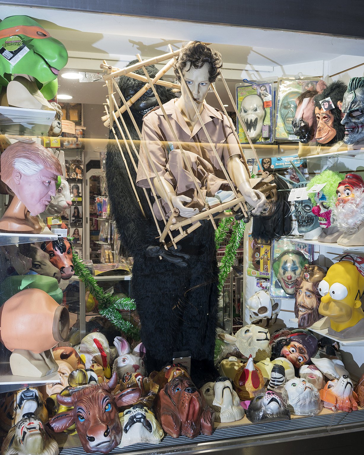 Group of horror masks and mannequins, including a prominent one holding a scaffold-like structure, in a store display.