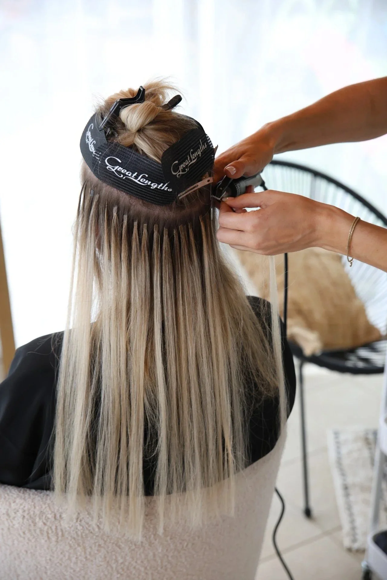Une coiffeuse en train de poser des mèches d'extensions Great Lenghts blondes