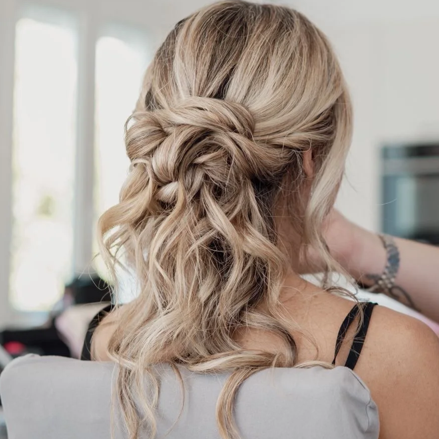 Cheveux blondes bouclés attachés en une coiffure élégante vue de dos.