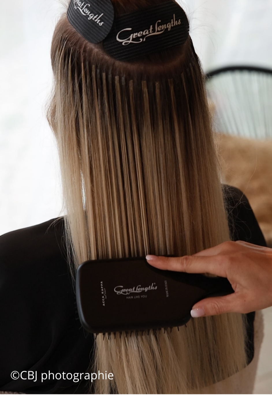 cliente se faisant poser des extensions, dont la coiffeuse brosse ses cheveux
