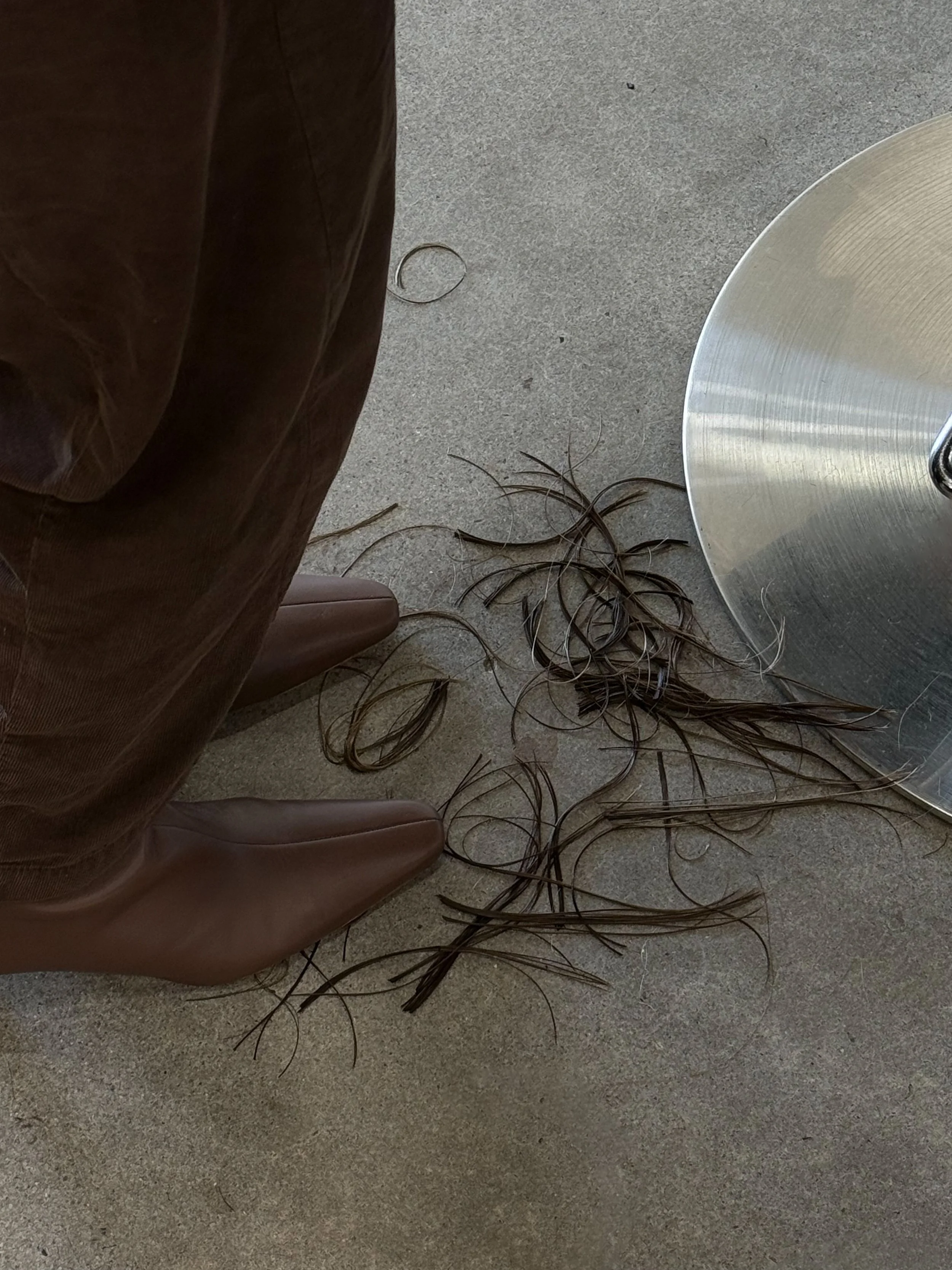 Brown hair strands on beige carpet next to table and furniture leg.