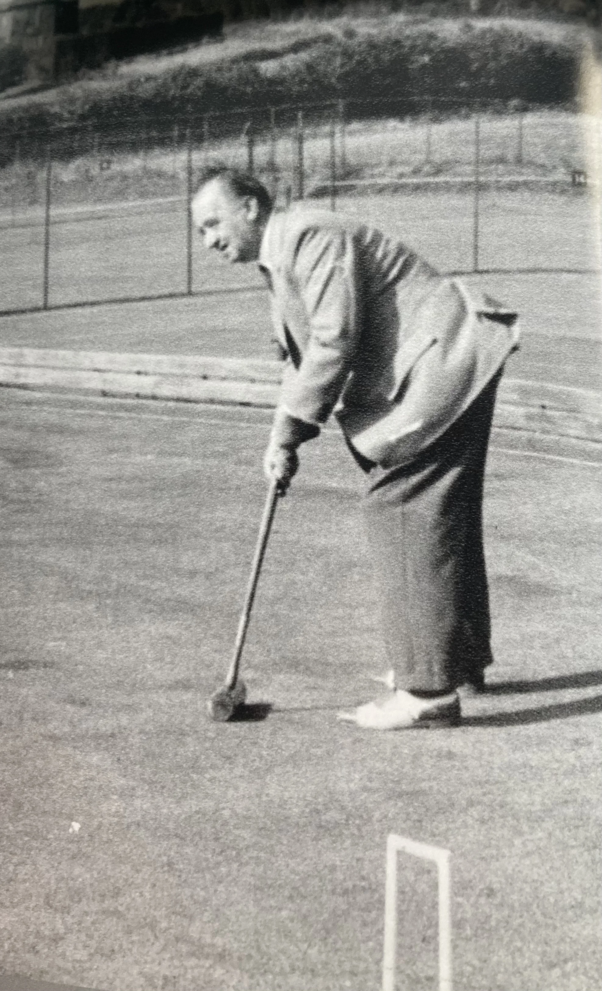 A man wearing traditional Japanese clothing playing mini-golf on an outdoor course.