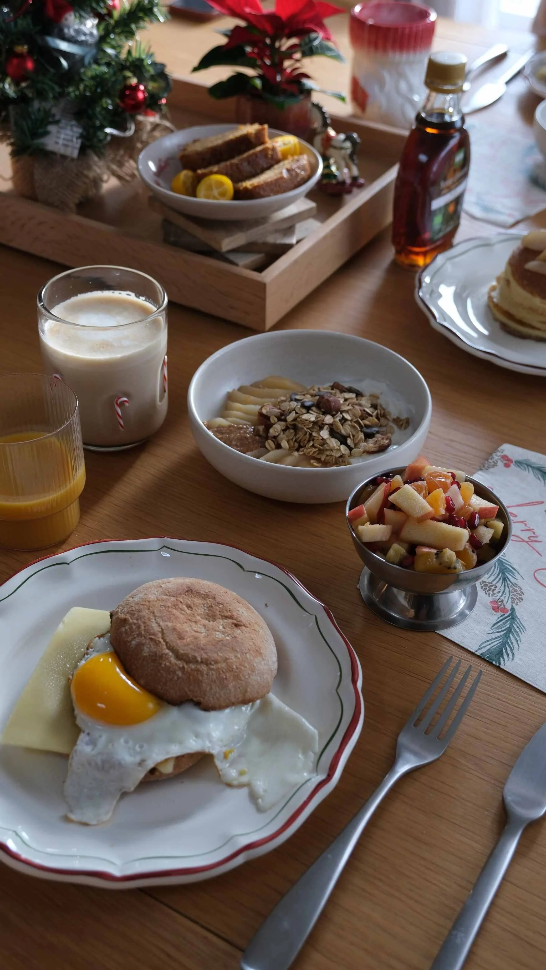Petit-déjeuner de Noël avec œuf au plat, biscuit, confiture, céréales, fruits, jus d'orange, lait, et décors de Noël.