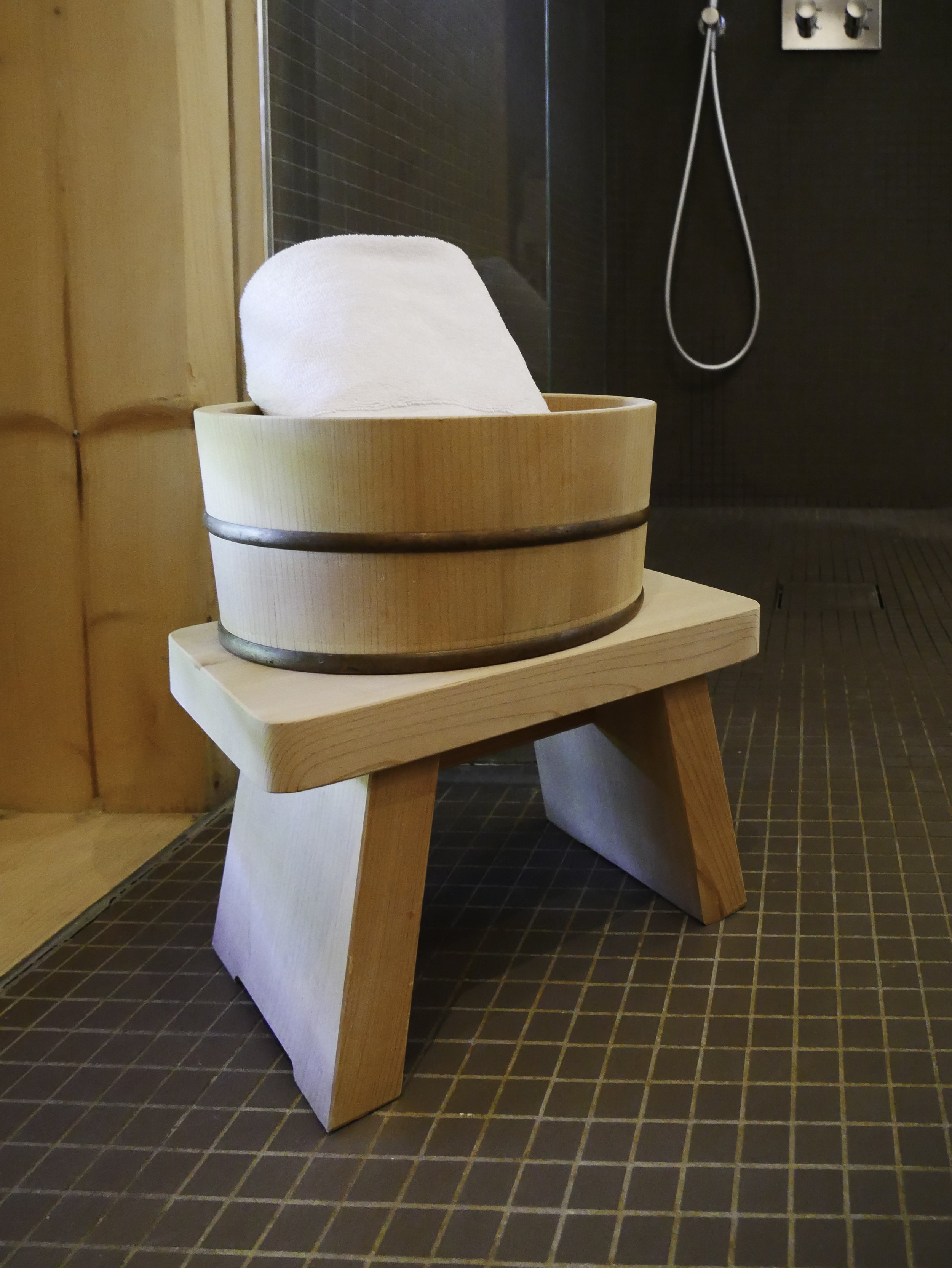 Seau en bois avec serviette blanche dans un sauna ou hammam.