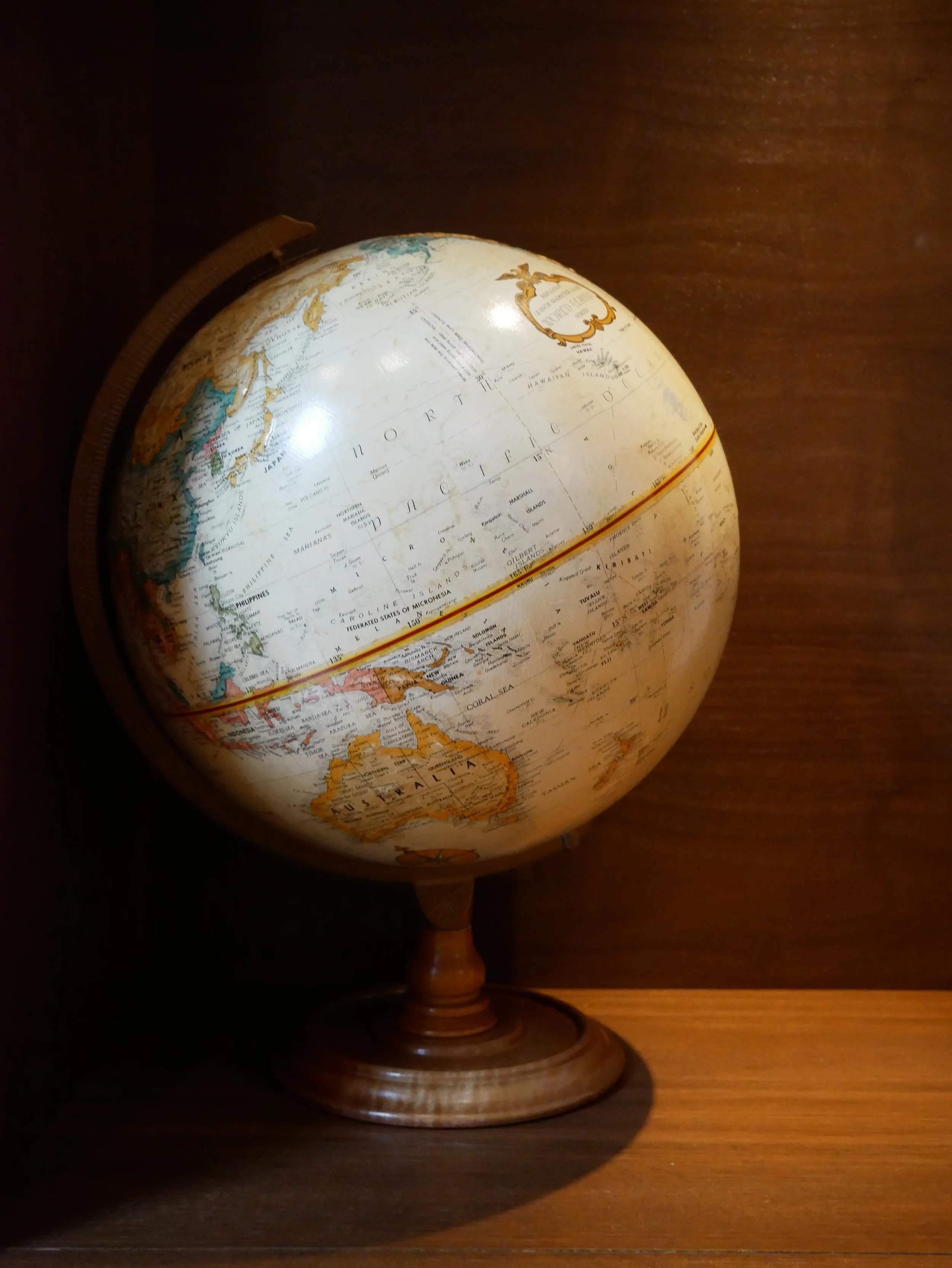 Un globe terrestre posé sur une surface en bois, avec un fond sombre.